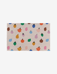 The Fruit Basket rug by Jennifer Bouron is a rectangular beige piece featuring gray G patterns and vibrant fruit and flower illustrations—a stylish, eco-friendly touch for any room.