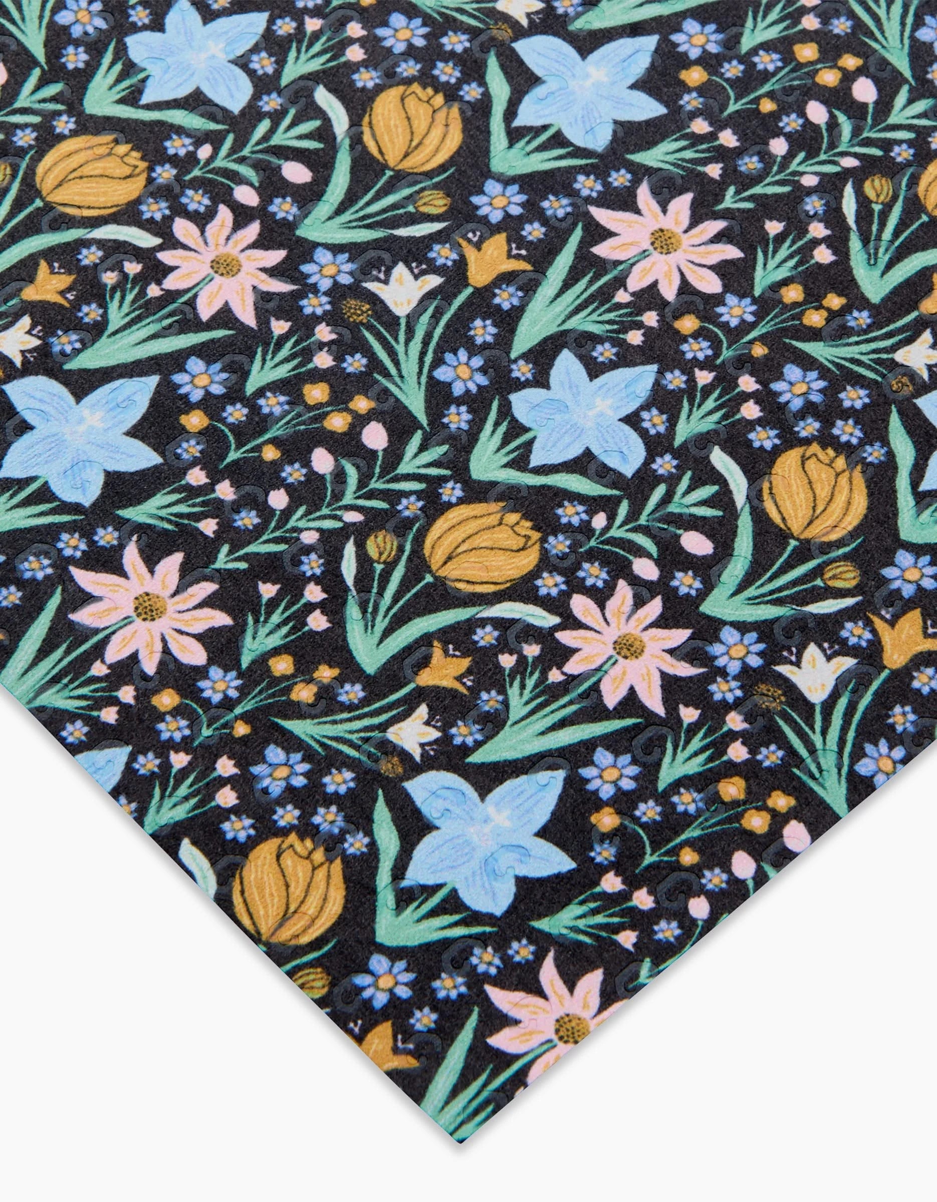 The Danelys Sidron Garden of Light sheet features blue, pink, and yellow floral patterns with green leaves on black post-consumer recycled paper, viewed at an angle to show a partial design.