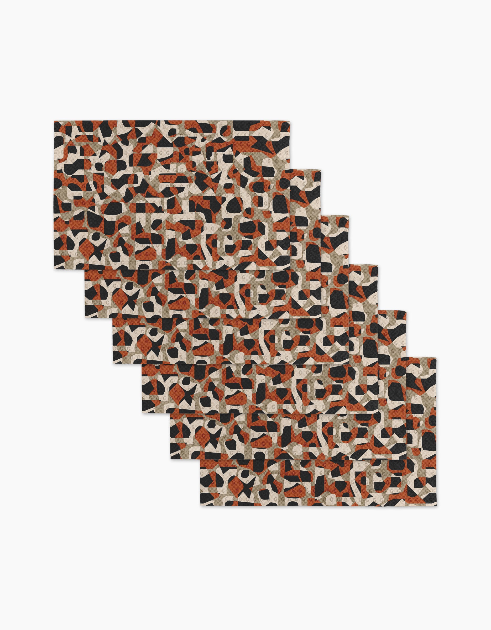 Six rectangular mats from Kris Ruff’s Geometric Leopard collection—featuring an abstract pattern in black, rust, beige, and cream—are arranged in a staggered overlap to evoke the style of eco-friendly paper towels on a white background.