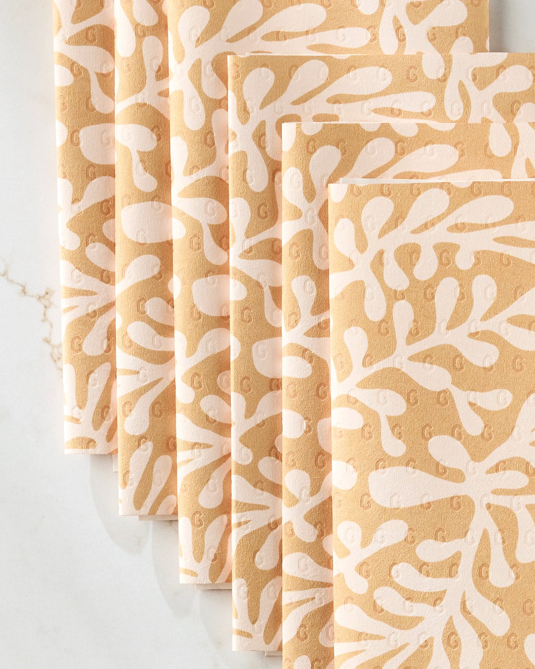 Golden Fall by GEOMETRY: a set of five peach reusable paper towels featuring a white abstract leaf and branch pattern, neatly fanned out on a white surface.