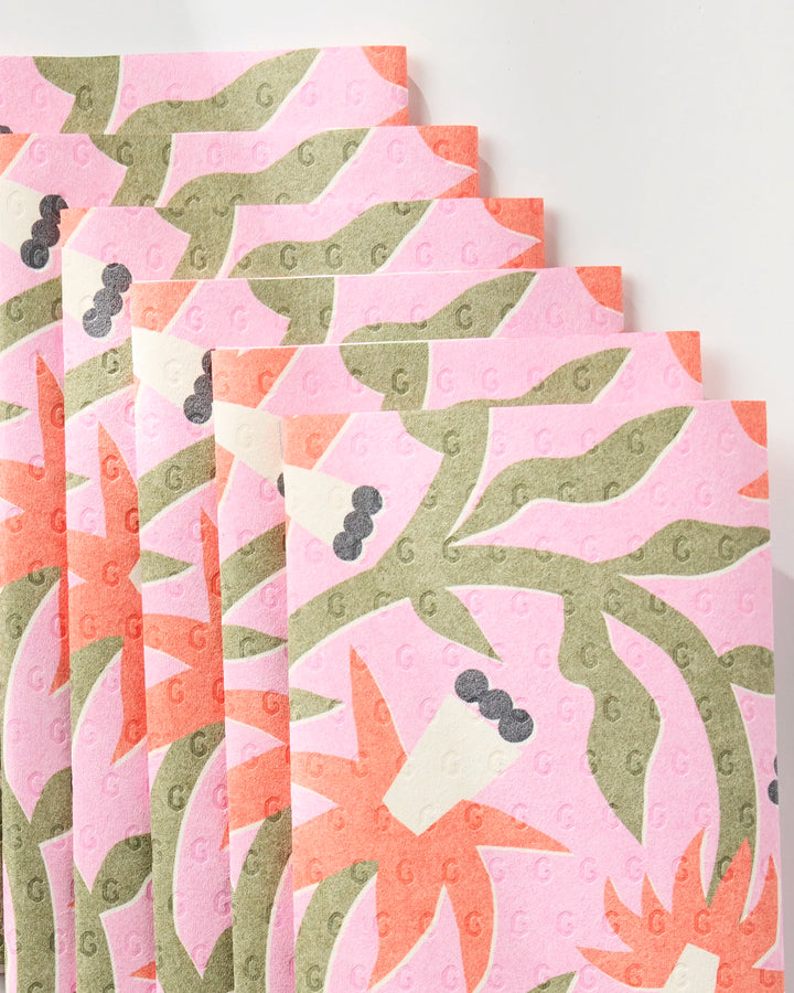 Claire Iglesias Graphic Flowers reusable paper towels feature a green and orange abstract floral pattern on pink and orange towels, shown overlapping in a fan arrangement on a white surface.