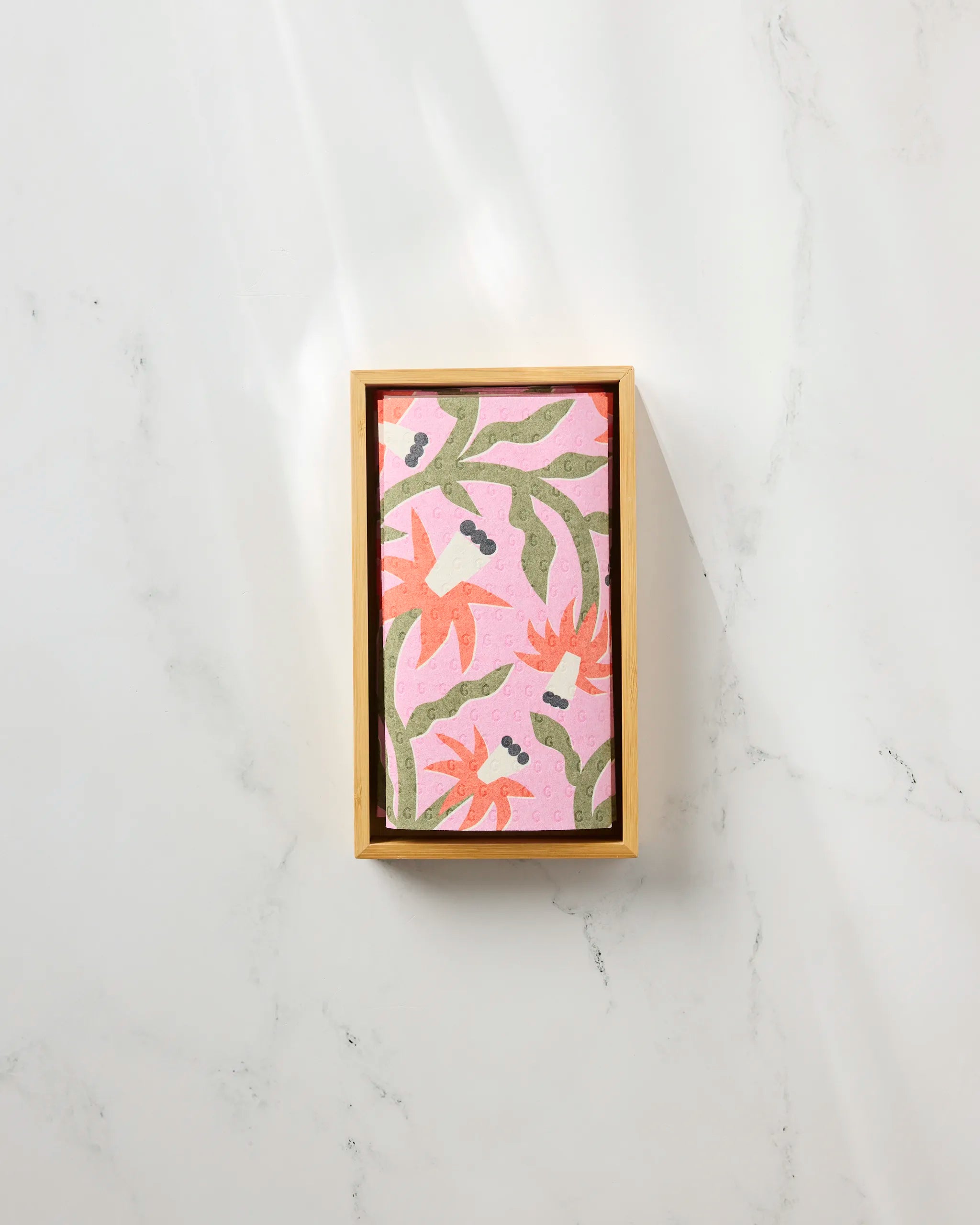 Claire Iglesias' Graphic Flowers is a rectangular box with a pink lid featuring an abstract floral pattern in orange, green, and purple—perfect for storing reusable paper towels on your white marble surface.