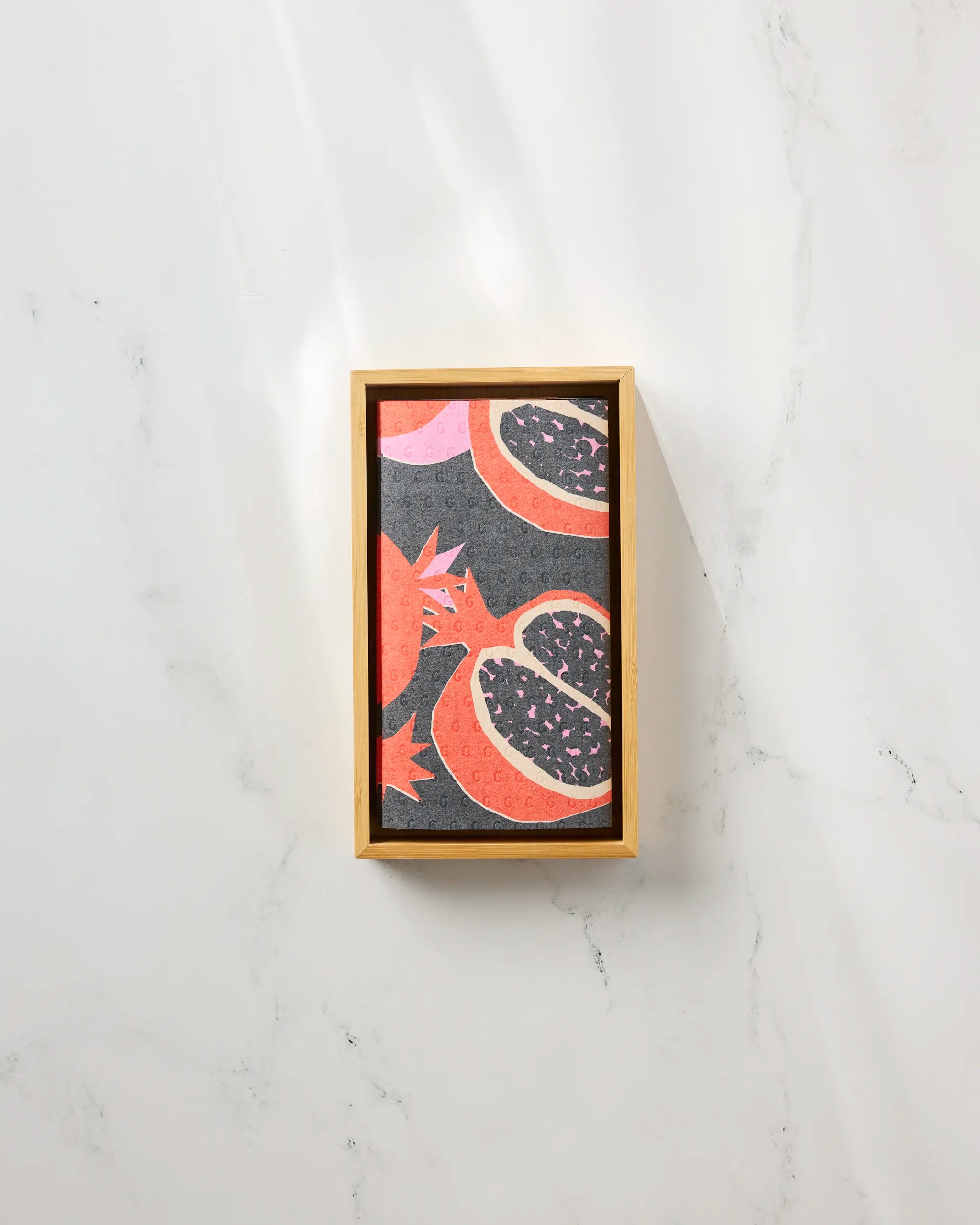 The Graphic Pomegranates jigsaw puzzle by Claire Iglesias features sliced pomegranates on a dark background in a rectangular wooden tray—an ideal eco-friendly touch for your sustainable home.