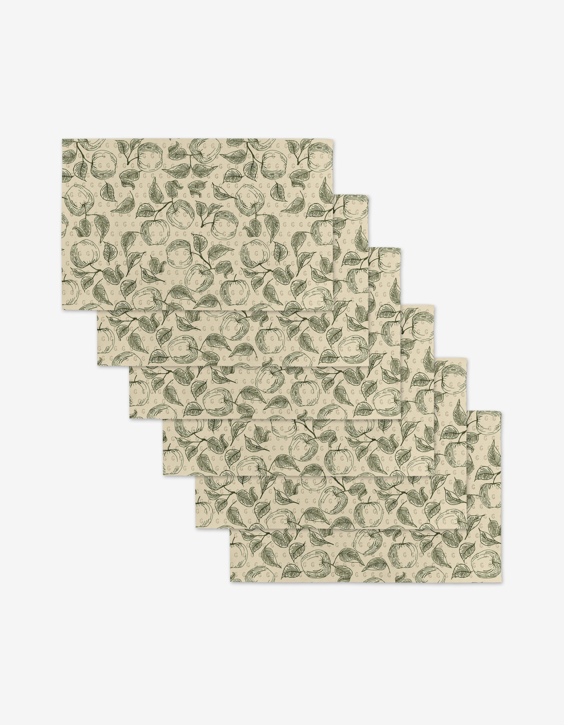 Five rectangular Gravenstein Apple placemats by Ash Cascade, beige with green botanical prints of leaves and fruit, are arranged in a staggered layout on a white background—an eco-friendly alternative to traditional placemats.