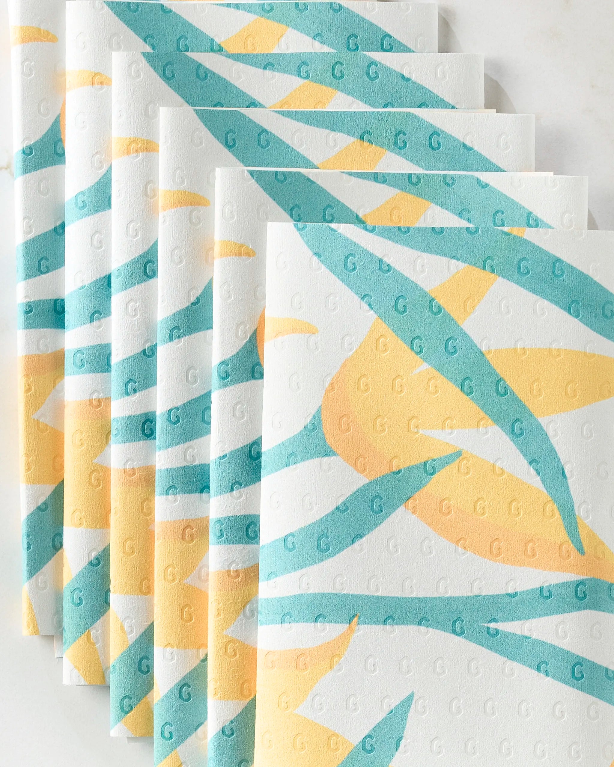 GEOMETRY’s "Growth" eco-friendly paper towels feature a teal and yellow leaf pattern with an embossed repeating “G” texture.