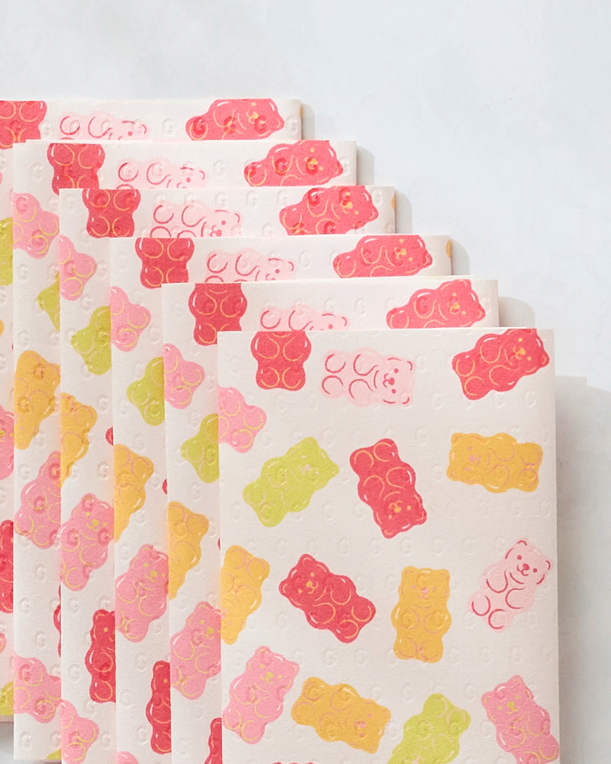 Vaishali Design Studio’s “Gummy Bear” reusable paper towels feature pink, yellow, orange, and green gummy bear illustrations in a neat, overlapping pattern on a light background.