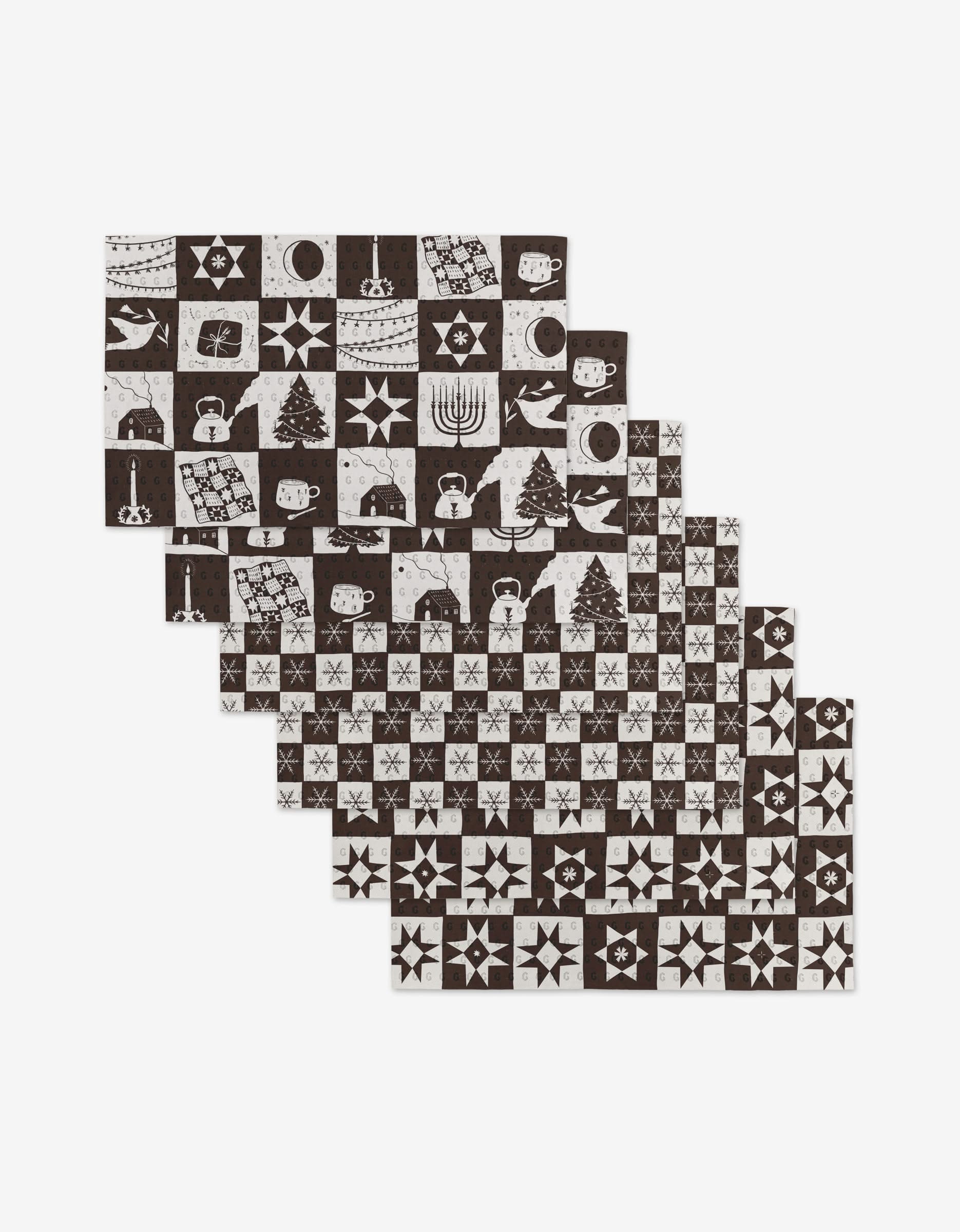 The Elana Gabrielle Holiday Love set includes six reusable rectangular placemats with black and white patchwork holiday motifs—menorahs, dreidels, trees, ornaments, and stars—offering an eco-friendly Not Paper Towel alternative.