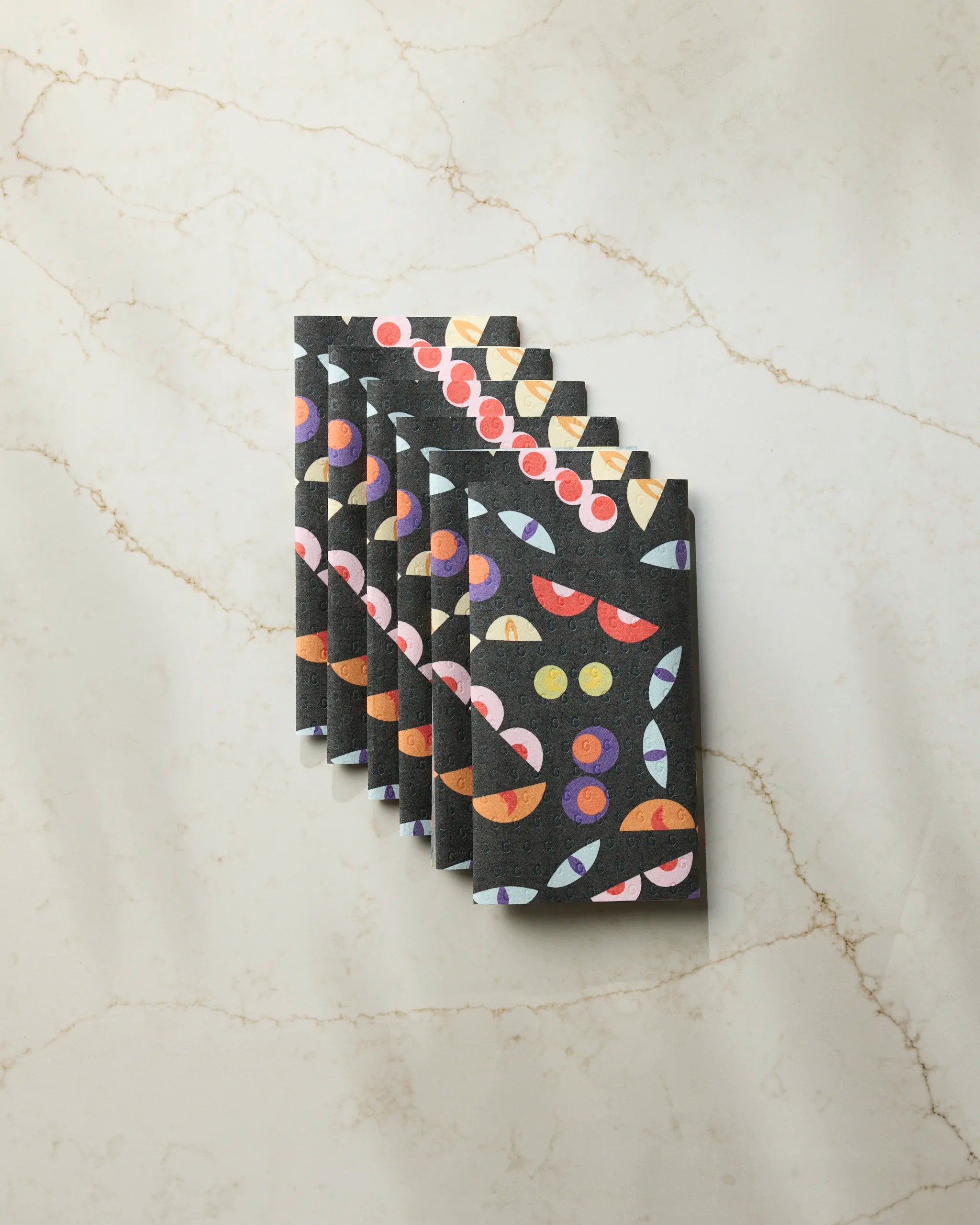 A stack of black "I See You" cards by Geometry, featuring colorful abstract shapes on a light marble surface with beige veining—perfect inspiration for eco-friendly or recycled paper towel designs.