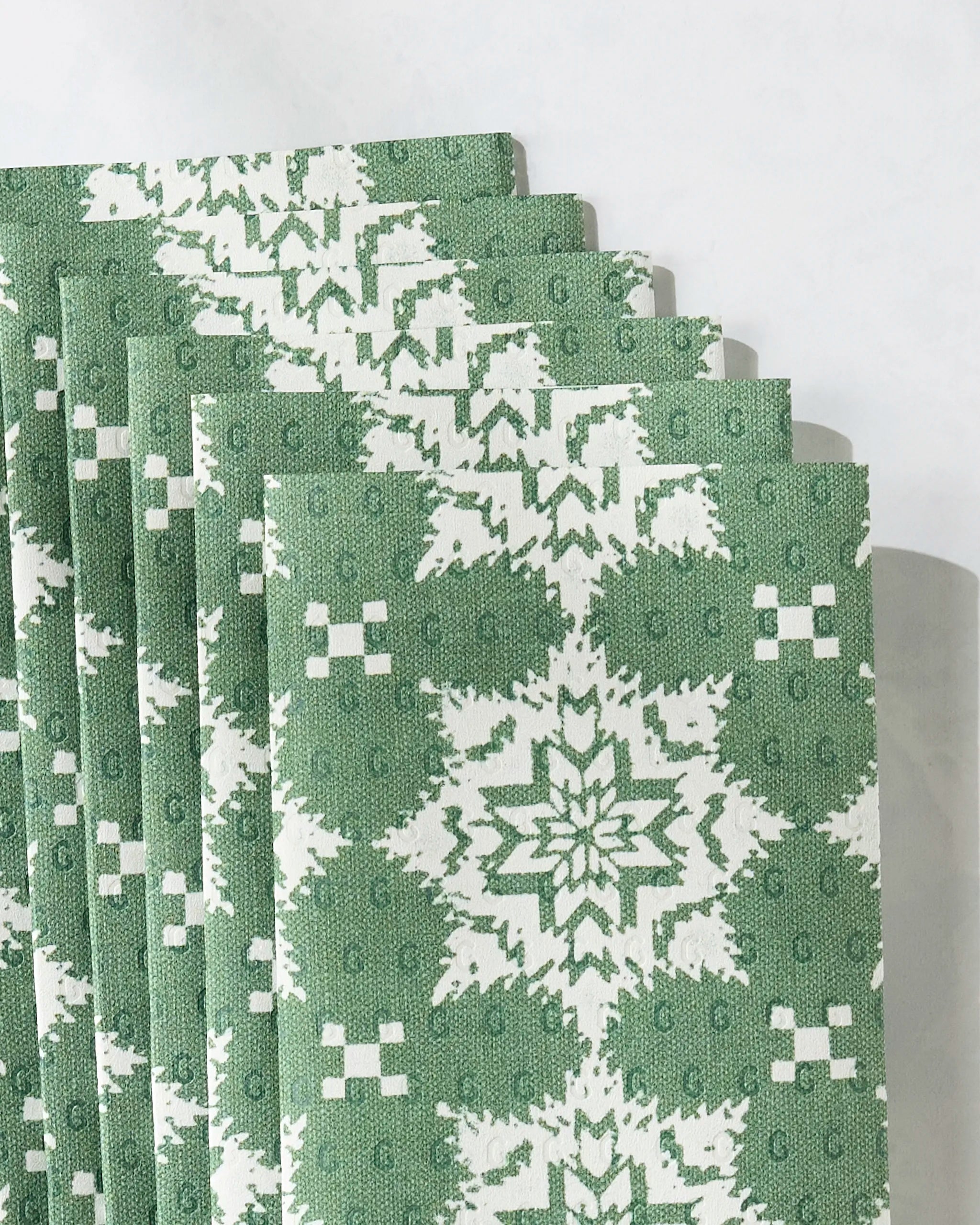 Geometry’s Iceflower Green cloth napkins, featuring a geometric star-like pattern in green and white, are neatly stacked—an eco-friendly alternative to paper towels for any kitchen.