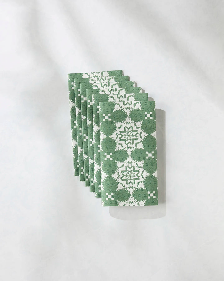 A stack of Geometry’s Iceflower Green reusable paper towels, featuring a symmetrical green and white floral pattern, is neatly arranged on a light surface, with shadows cast to the right.
