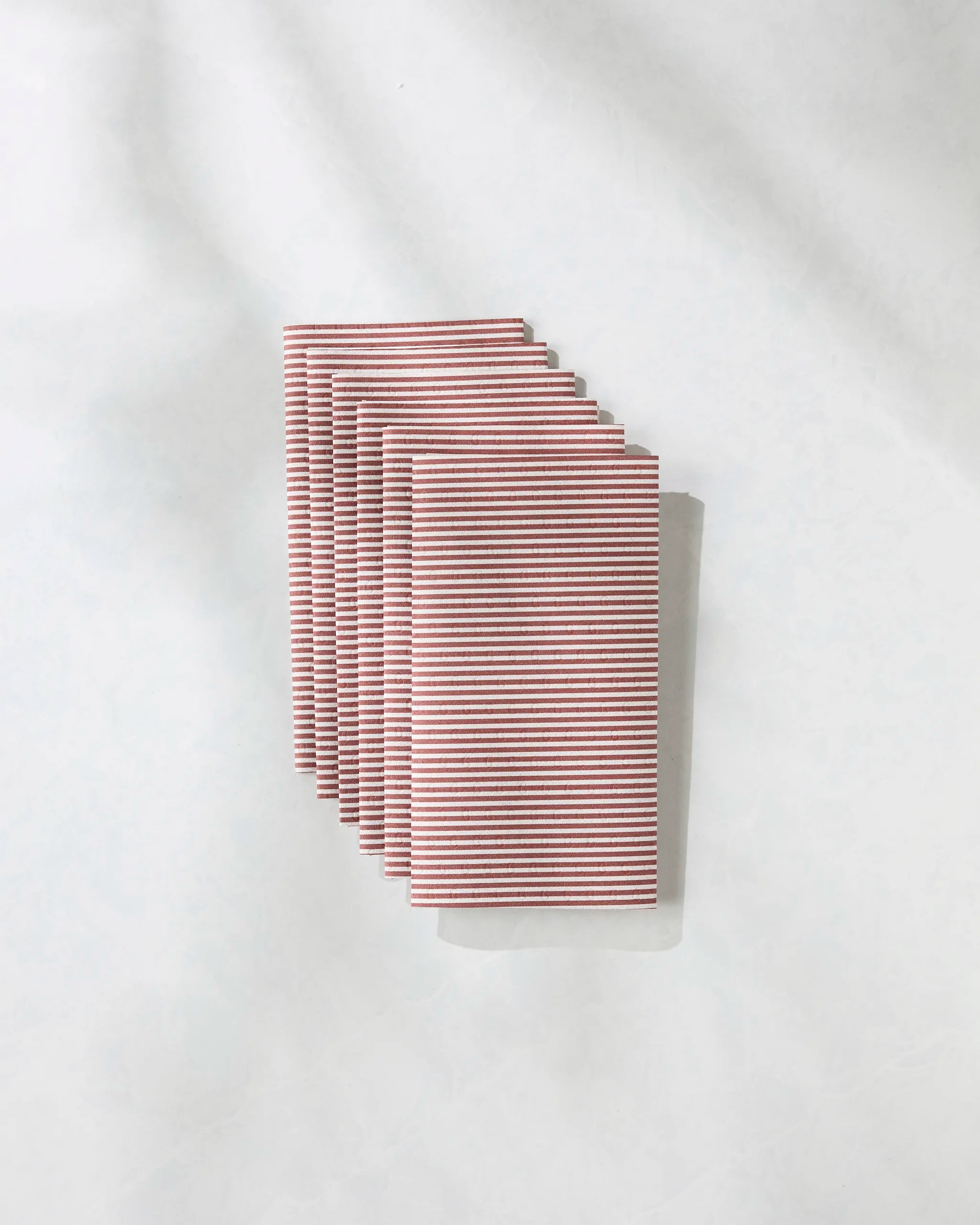 Six eco-friendly Geometry Kringle kitchen towels, neatly stacked with thin red and white stripes on a light textured surface—an attractive and sustainable alternative to Not Paper Towels.