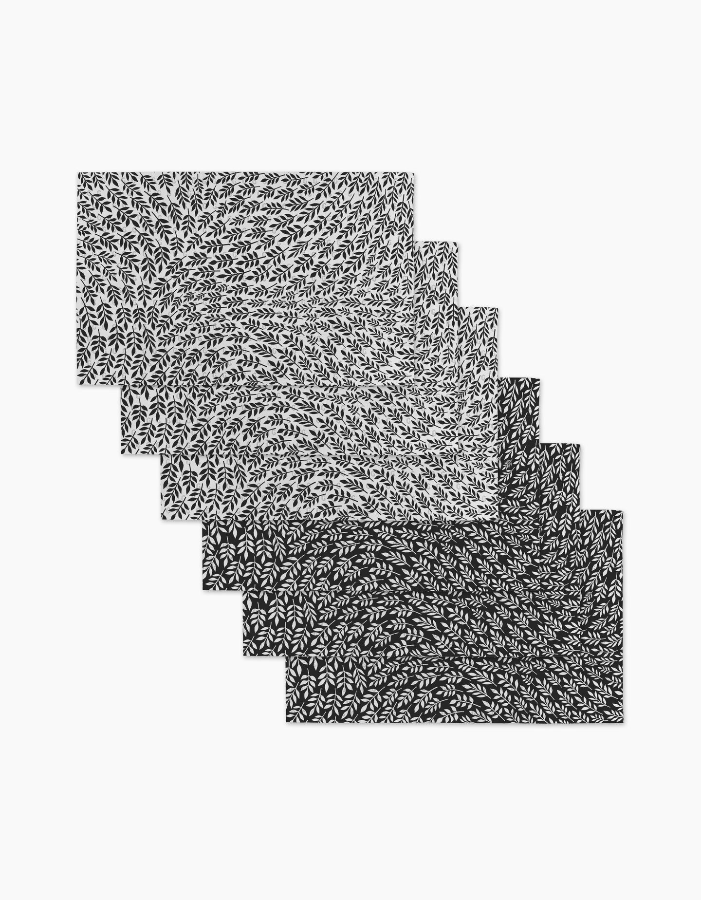 Six rectangular Leaf Swirls placemats by Rachel Parker are stacked with a black and white swirling leaf design that fades from light to dark—made from eco-friendly, reusable paper towels for sustainable style.