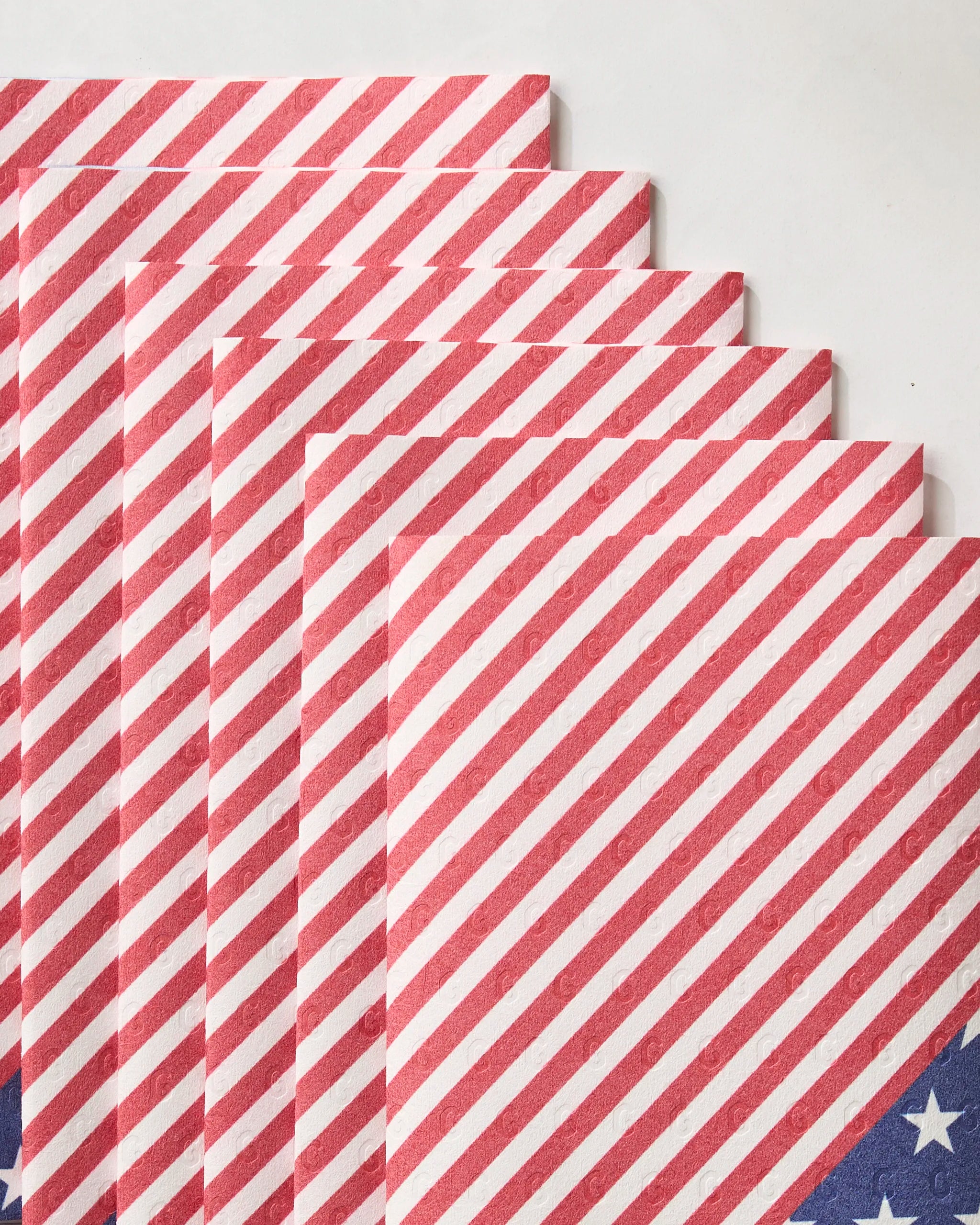 Geometry’s Liberty eco-friendly kitchen towels are neatly stacked, showing red diagonal stripes and a corner of white stars on blue—evoking the American flag.