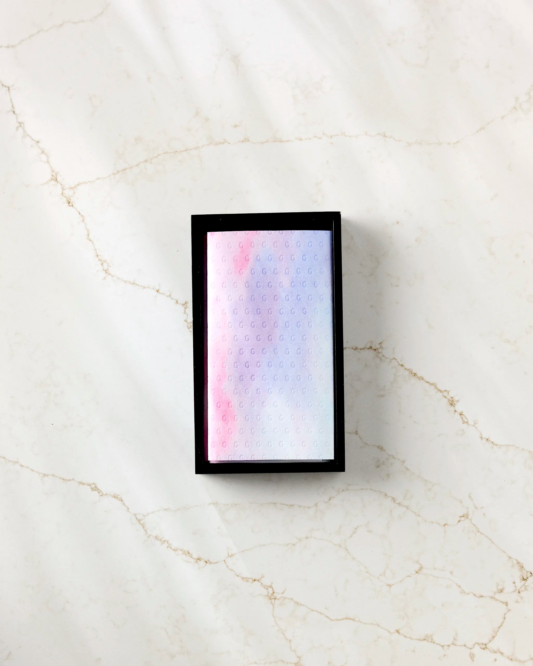 The Magic In The Sky box by Stefanie Bales, a small rectangle with a pastel lid and raised dot pattern, designed for eco-friendly kitchen towels, rests on a white marble surface with light brown veining.