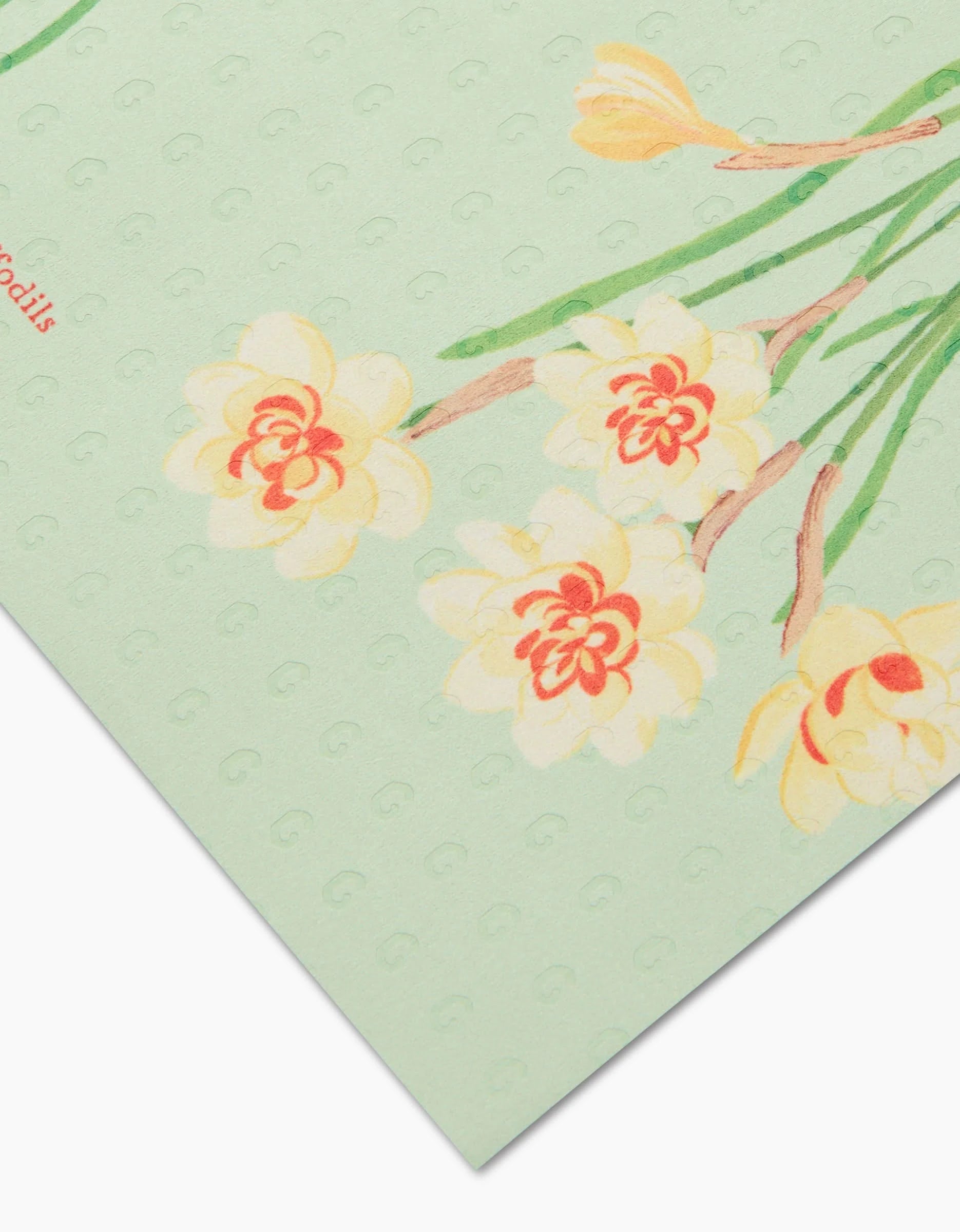 A close-up of March Daffodils by Linda Fox shows pale yellow and orange daffodil illustrations on light green textured, post-consumer recycled paper, with a corner of the sheet in view.