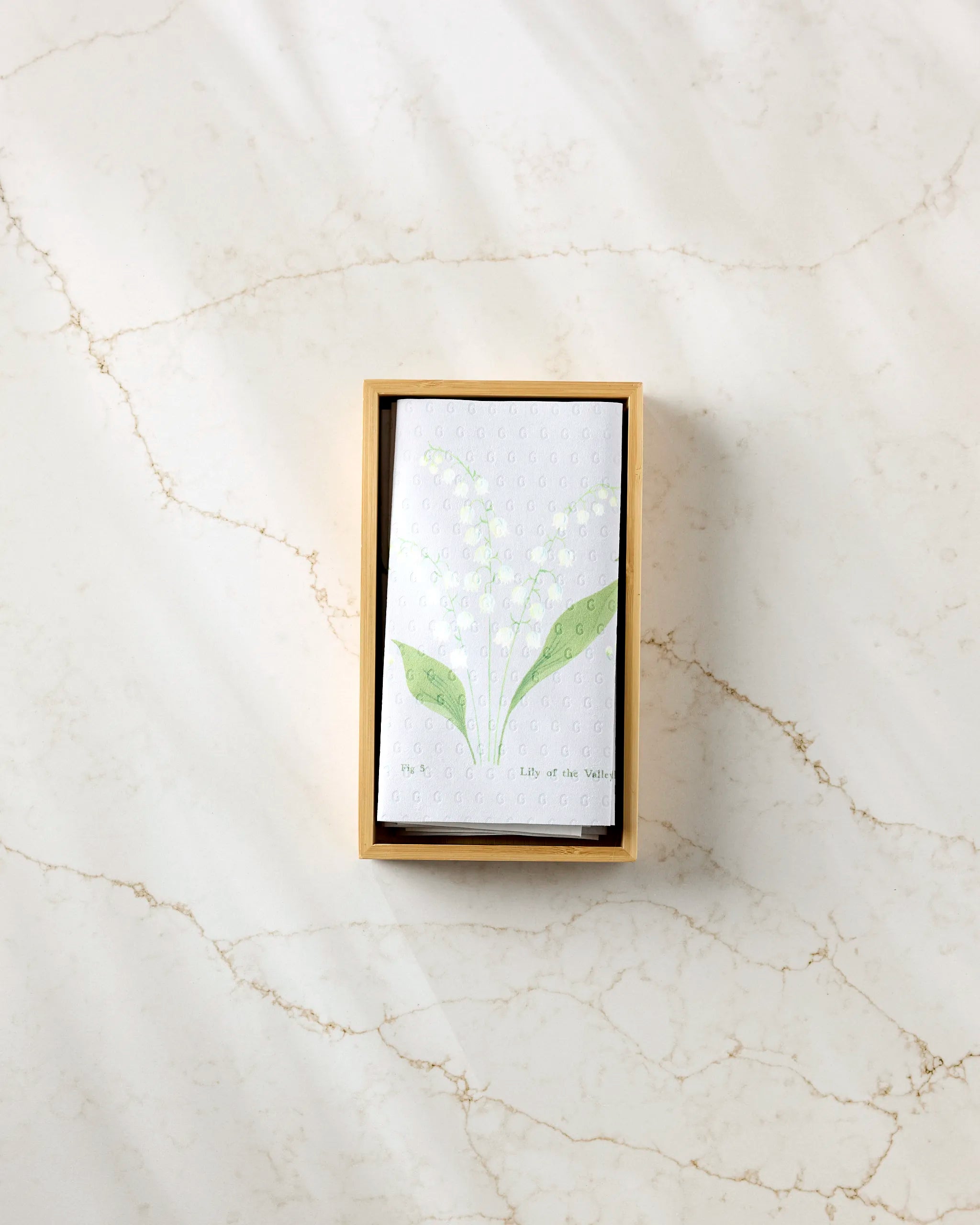 A small rectangular box from Linda Fox holds the May Lilly Of The Valley card, featuring minimalist flower art. It pairs beautifully with eco-friendly kitchen towels for a sustainable touch.