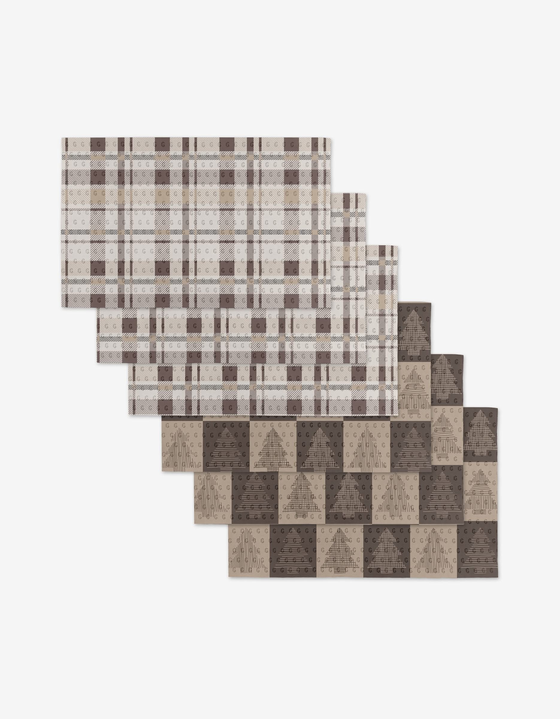 Four rectangular, reusable placemats from Rosa Kichline, featuring a Minimal Christmas Trees design, are arranged in an overlapping pattern on a white background—an eco-friendly choice.