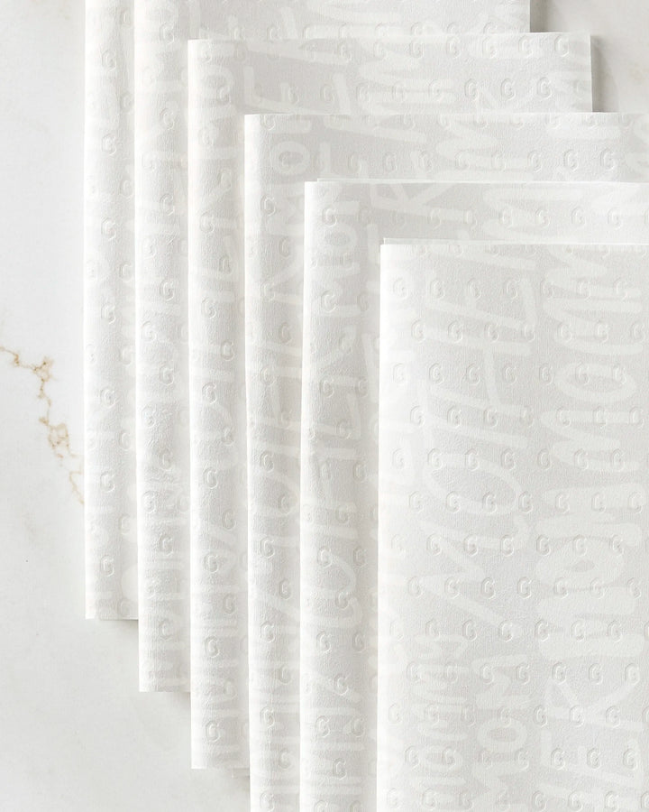 GEOMETRY's Mom reusable paper towels, featuring a subtle embossed pattern, are fanned out on a white marble surface with delicate veining.