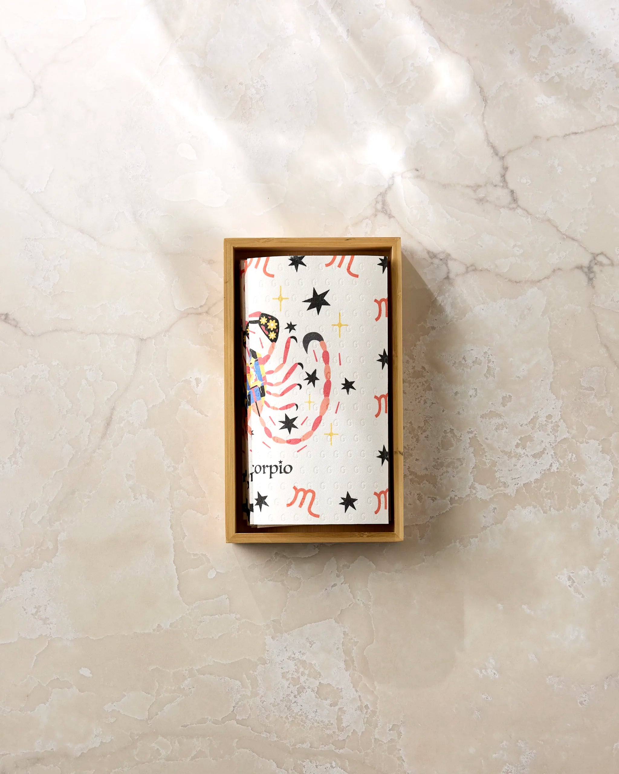 The Mysterious Scorpio card by Heather Zhou, featuring black stars, red Scorpio symbols, and a pink-yellow scorpion in a rectangular wooden box on marble—ideal to pair with eco-friendly paper towels for sustainable gifting.