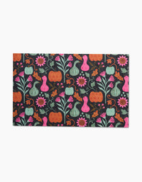 The Oakley rectangular mat by Amy MacCready features pumpkins, gourds, flowers, and leaves in orange, pink, teal, and green on a dark background—ideal for pairing with eco-friendly kitchen towels.