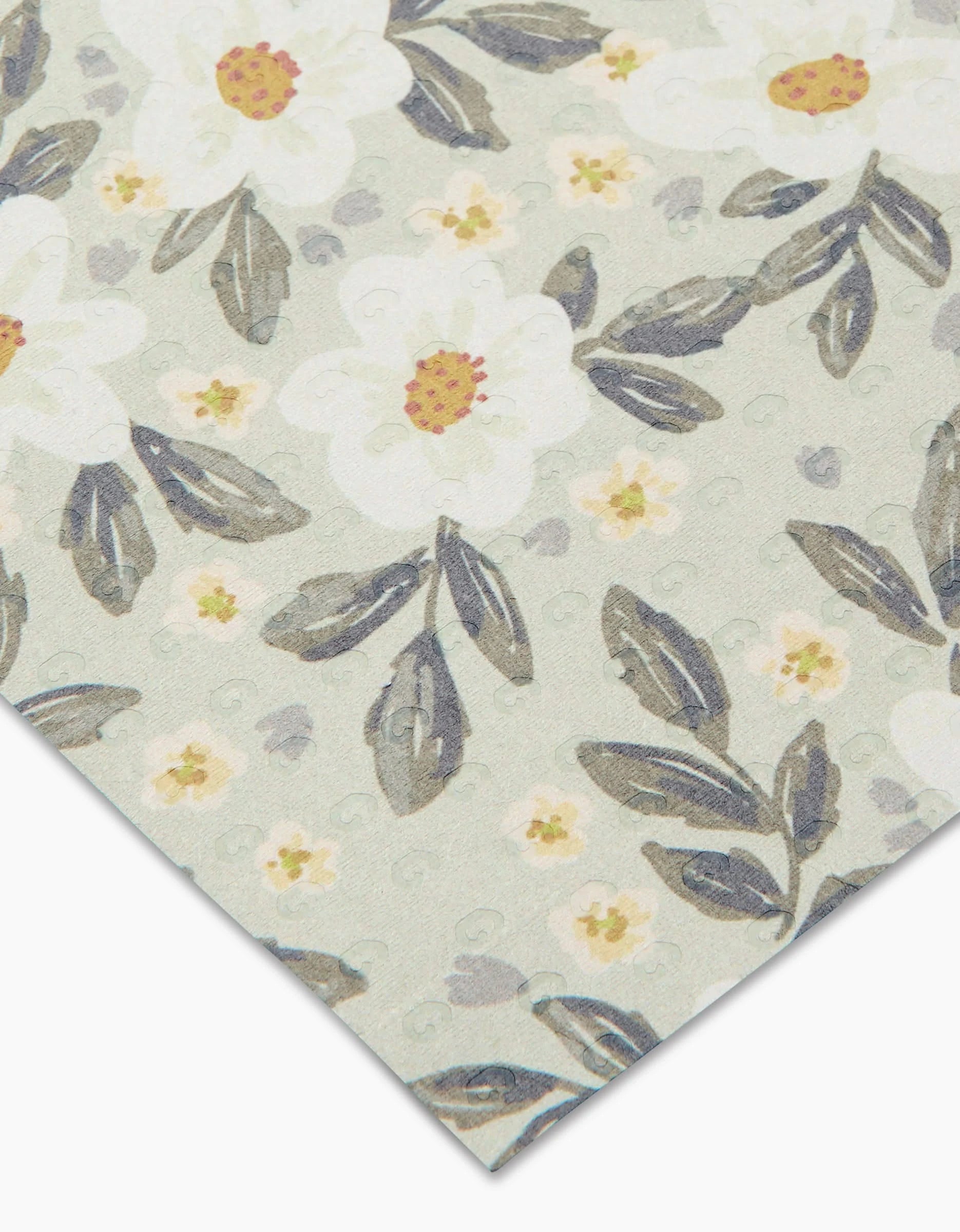 A close-up of Teri the Butters Painted Spring Flowers paper shows white flowers with yellow centers and greenish-gray leaves on a pale background, made from post-consumer recycled materials. The paper’s corner appears in the lower right.