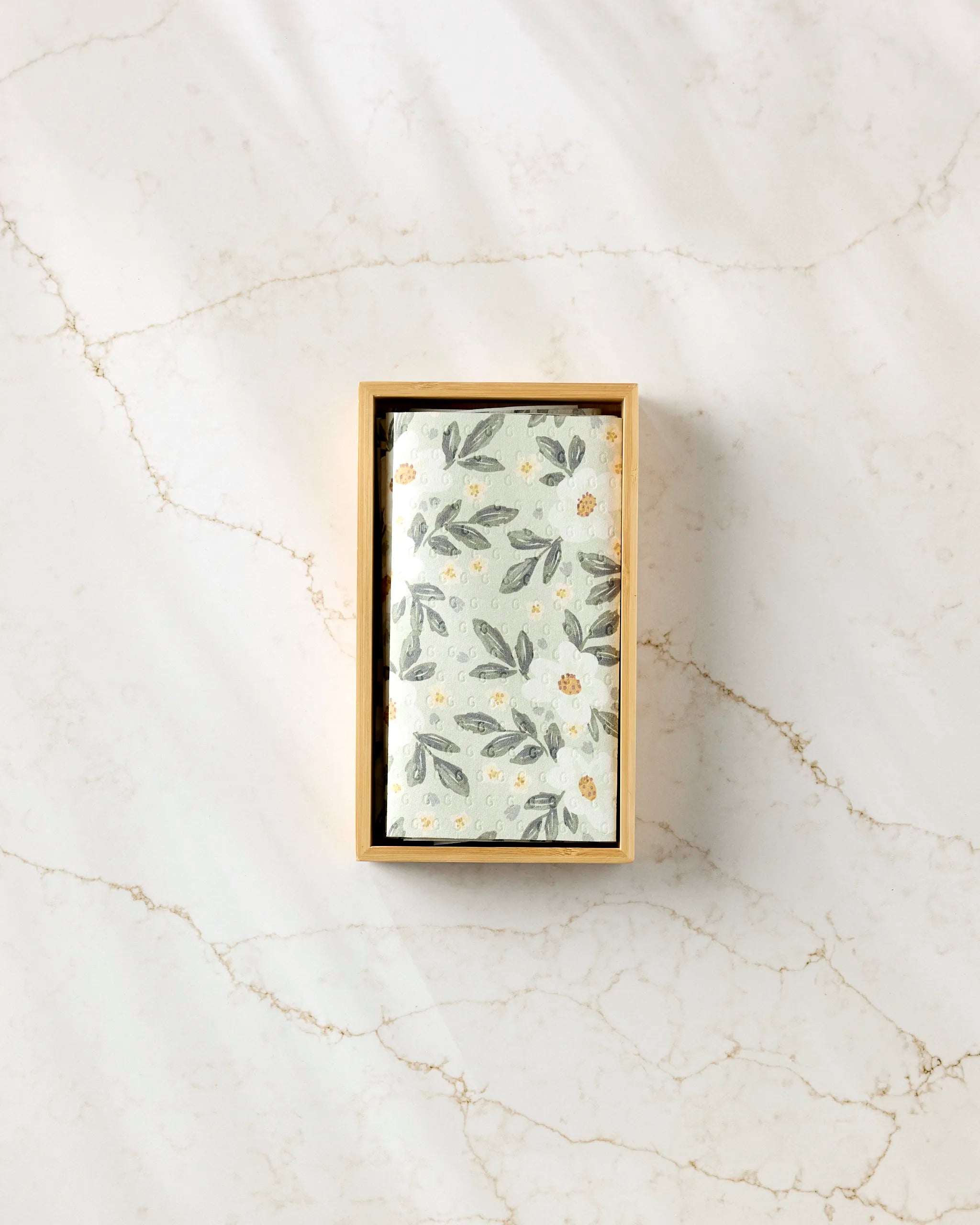 A rectangular box of Teri the Butter's Painted Spring Flowers reusable paper towels sits on a white marble surface with gold veining.