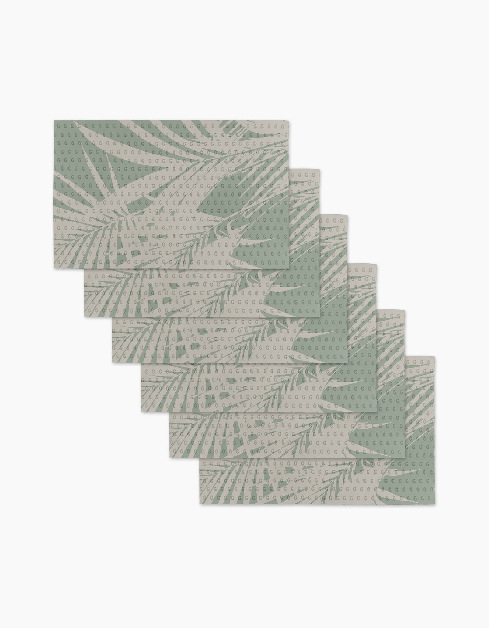 Six Palm Breeze rectangular placemats by Geometry are stacked in a fan arrangement, featuring a light green botanical leaf pattern on beige with dotted details. Made from recyclable materials, they offer an eco-friendly alternative to paper products.