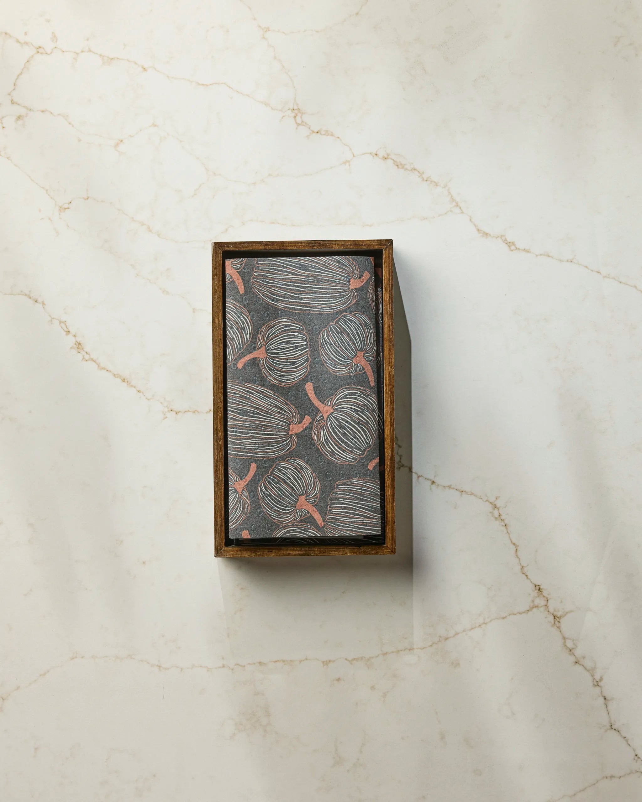 The Geometry Pinstripe Patch is a rectangular wooden box with a lid showcasing an abstract gray circle pattern and red accents, ideal for storing reusable paper towels, displayed on light marble with subtle brown veining.