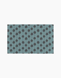 Polka Dot Blooms by Lizzie Clark is a rectangular mat featuring evenly spaced, simple black stylized trees on a muted blue background. This minimalist design brings eco-friendly, sustainable style to any space.