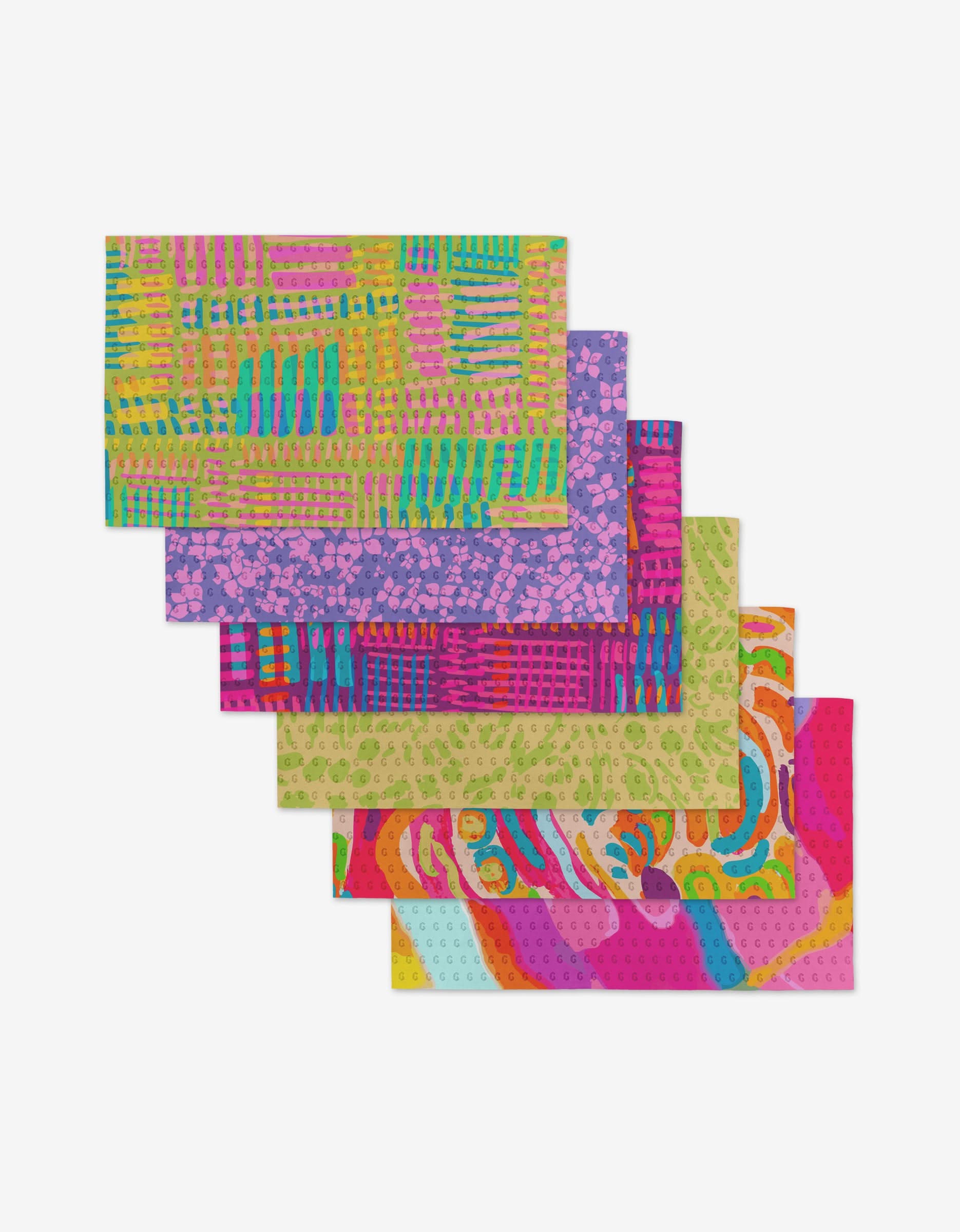 Six reusable cloths from Sareka Unique’s Positive Vibes set, each featuring vibrant abstract patterns, are layered and fanned out against a white background as an eco-friendly Not Paper Towels alternative.