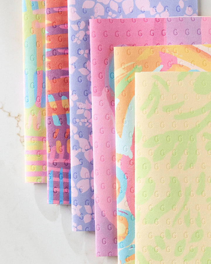 Six vibrant Sareka Unique "Positive Vibes" reusable paper towels, each with embossed dots and unique pastel patterns like stripes and abstracts, are neatly arranged on a white marble surface.