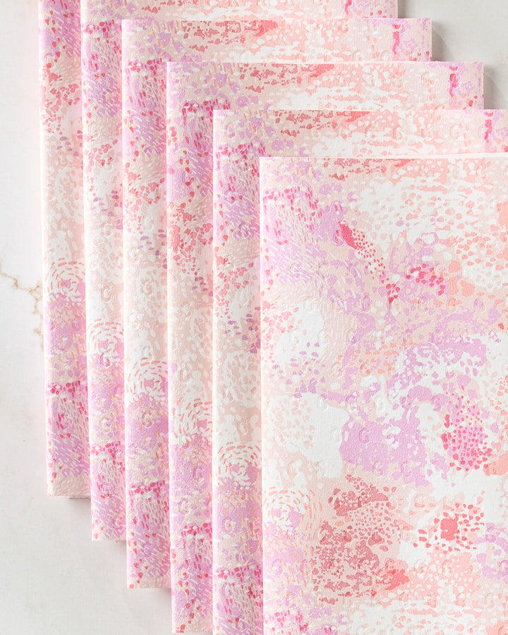 Six Elisabeth Wing Rawhide reusable paper towels, featuring a pink, peach, and lavender abstract floral pattern, are displayed in a fan shape on marble—an eco-friendly way to brighten your kitchen decor.