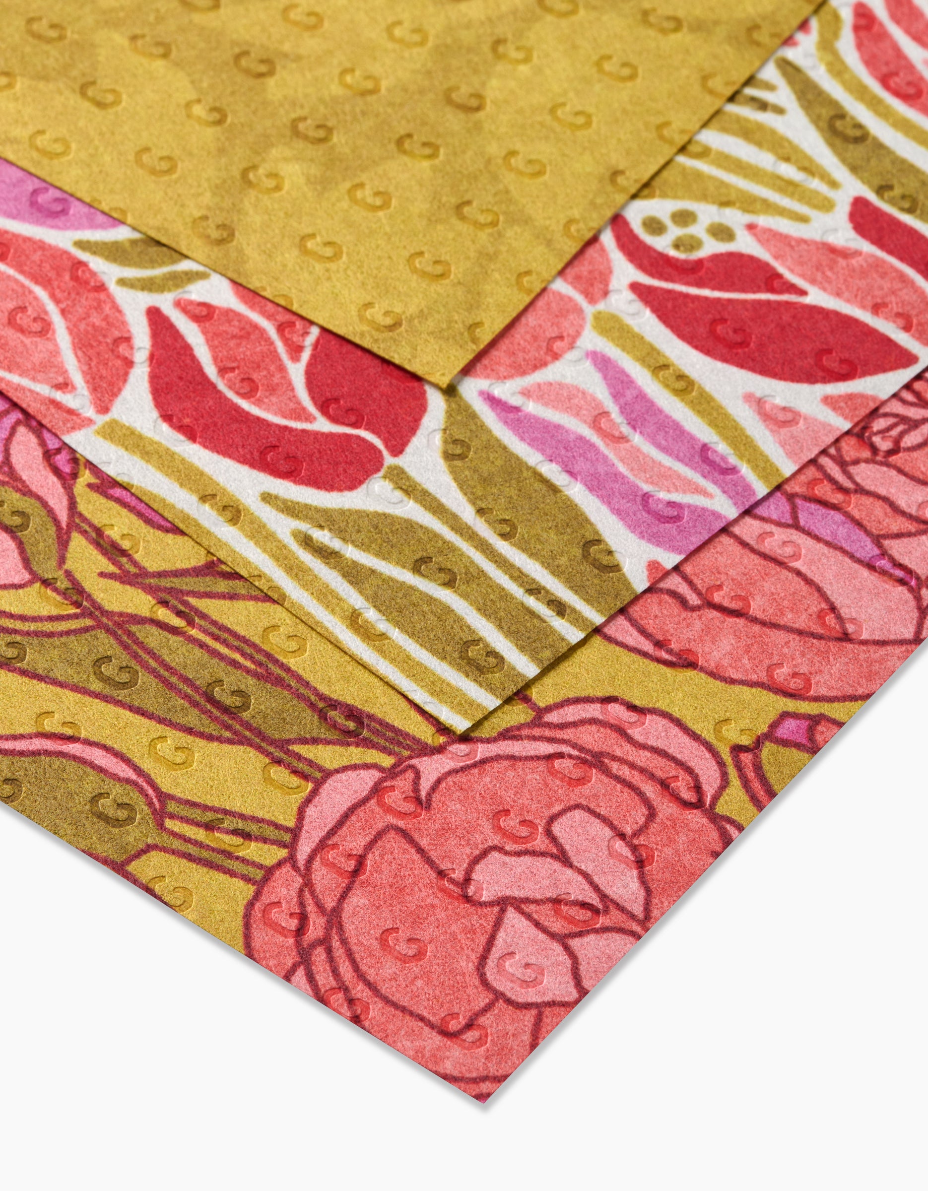 Sidney by Amy MacCready features three recycled sheets: one solid gold with small G prints and two with pink and red floral designs accented in gold—combining sustainability with elegant, eco-friendly style.