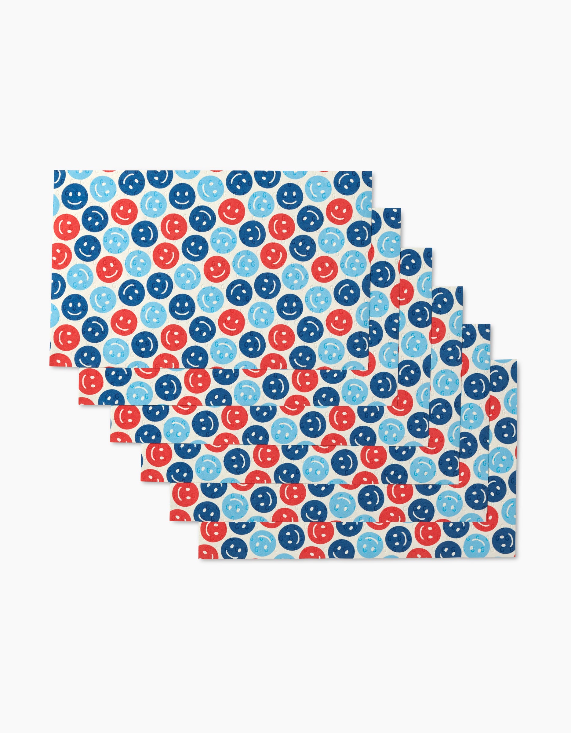Six overlapping rectangular Smiley Face July Blue Not Paper Towels by Hufton Studio feature blue, light blue, and red smiley faces on white, made from eco-friendly post-consumer recycled materials.