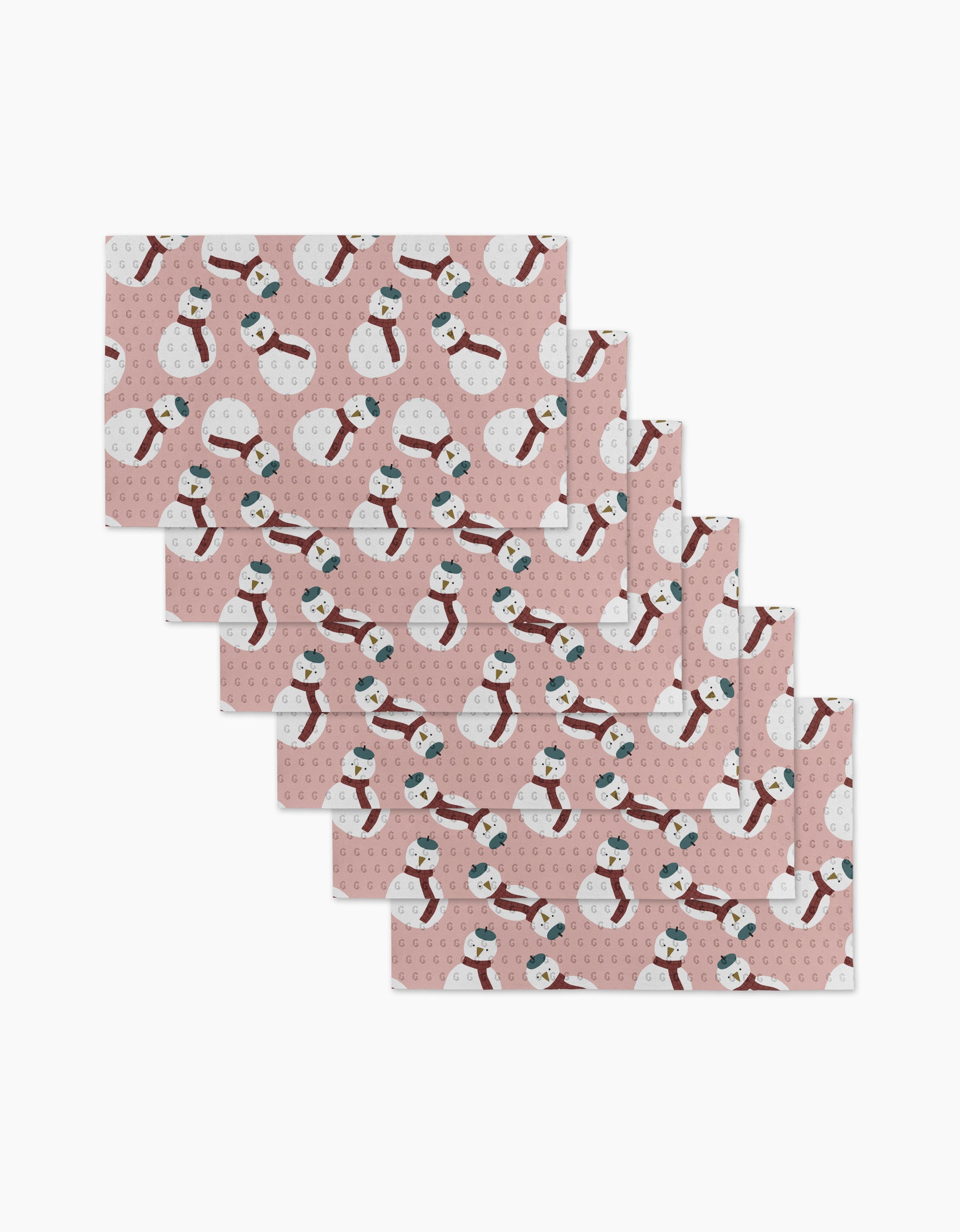 Jennifer Bouron's "Snowman" envelopes feature pink backgrounds with repeating snowmen in red scarves and blue hats, surrounded by white and pink dots. Made from recycled paper towels, they come neatly arranged in a staggered stack.