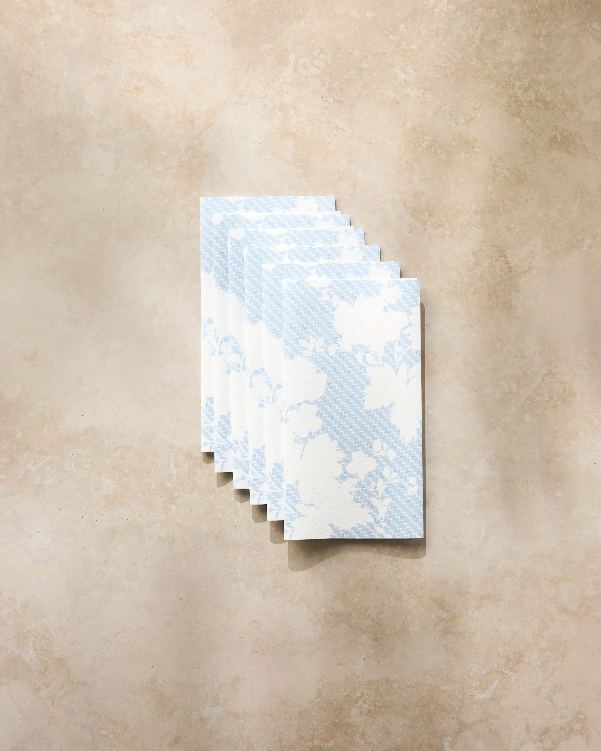 Six Soft Bloom envelopes by Geometry, featuring blue and white floral patterns, are displayed on a beige surface—ideal for stylishly gifting eco-friendly kitchen towels or reusable paper towels in a sustainable way.