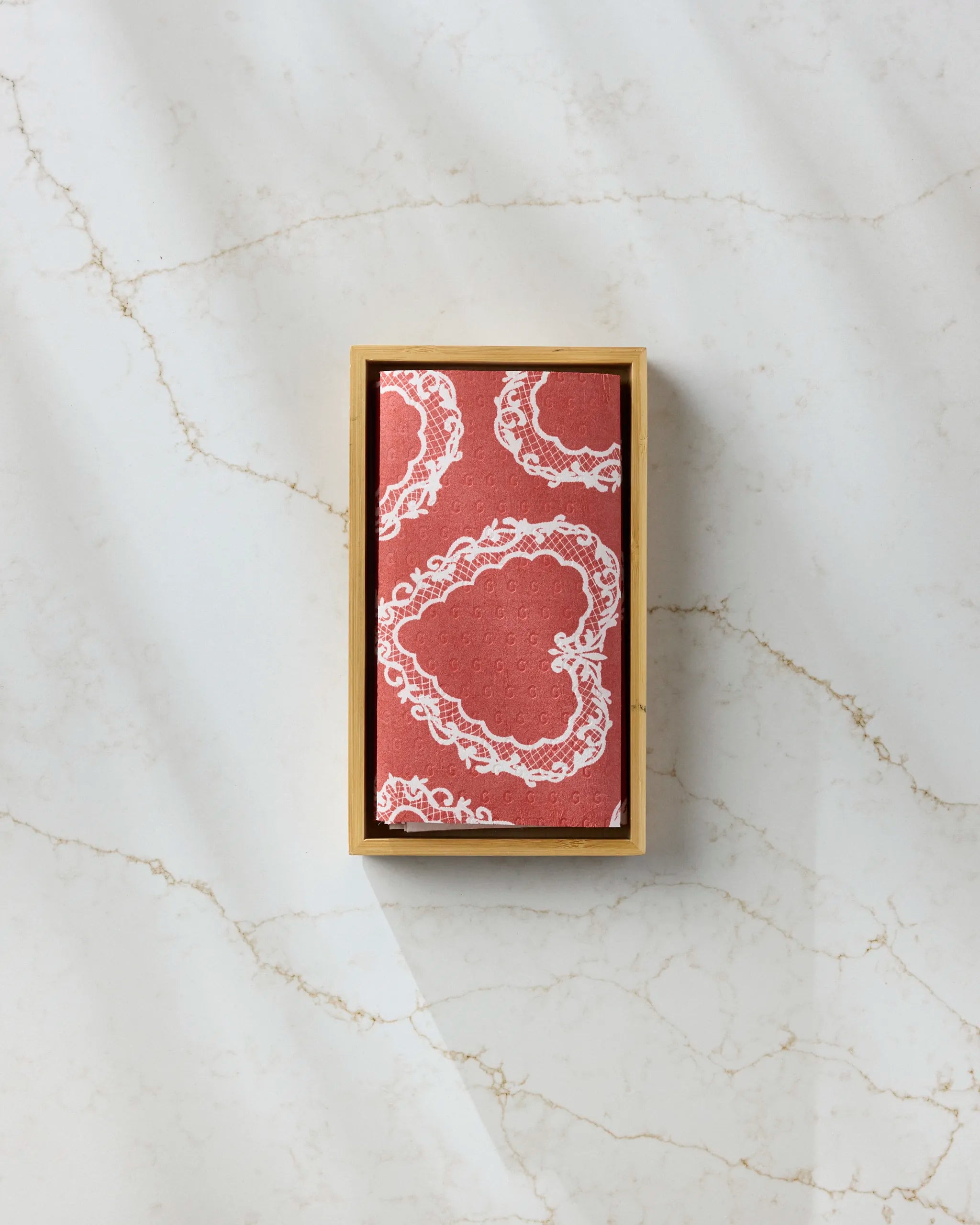 The Soft Heart Scarlet by Geometry—a rectangular box containing a red and white heart-patterned eco-friendly paper towel—rests on a light marble surface with subtle gold veining.