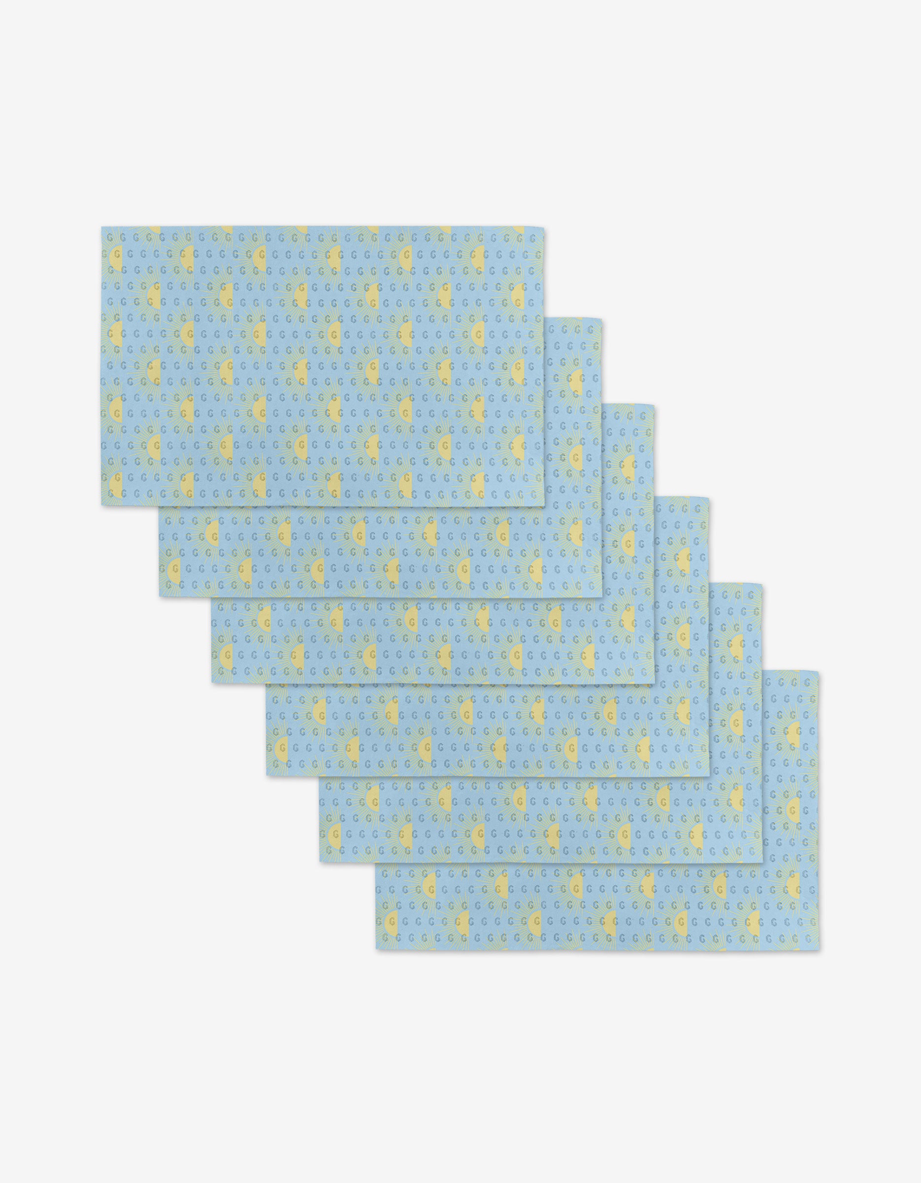 Six Soft Summer Sun rectangular blue placemats by GEOMETRY, featuring small yellow duck and blue circle patterns, made from eco-friendly post-consumer recycled materials, are fanned out and overlapping on a white background.