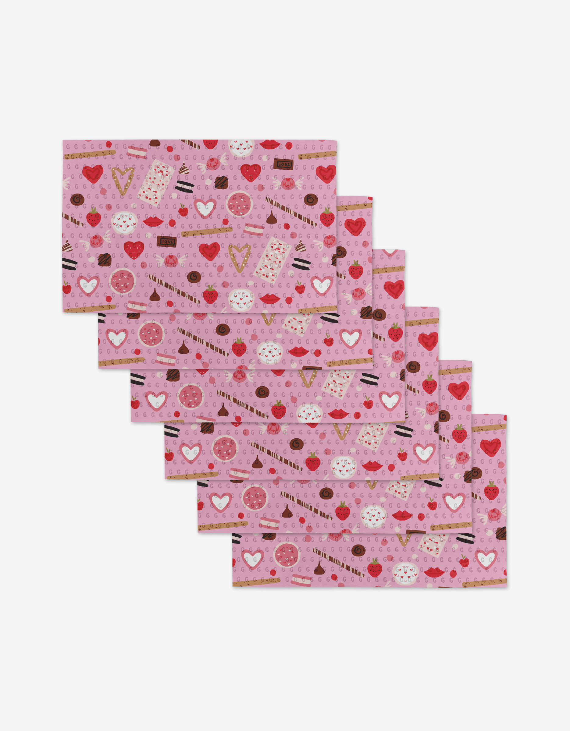Janna Sue Designs Sweet Lovin set includes six pink rectangular placemats made from eco-friendly recycled materials, each with a heart, donut, cupcake, chocolate, and sprinkle pattern displayed fanned out on a white background.