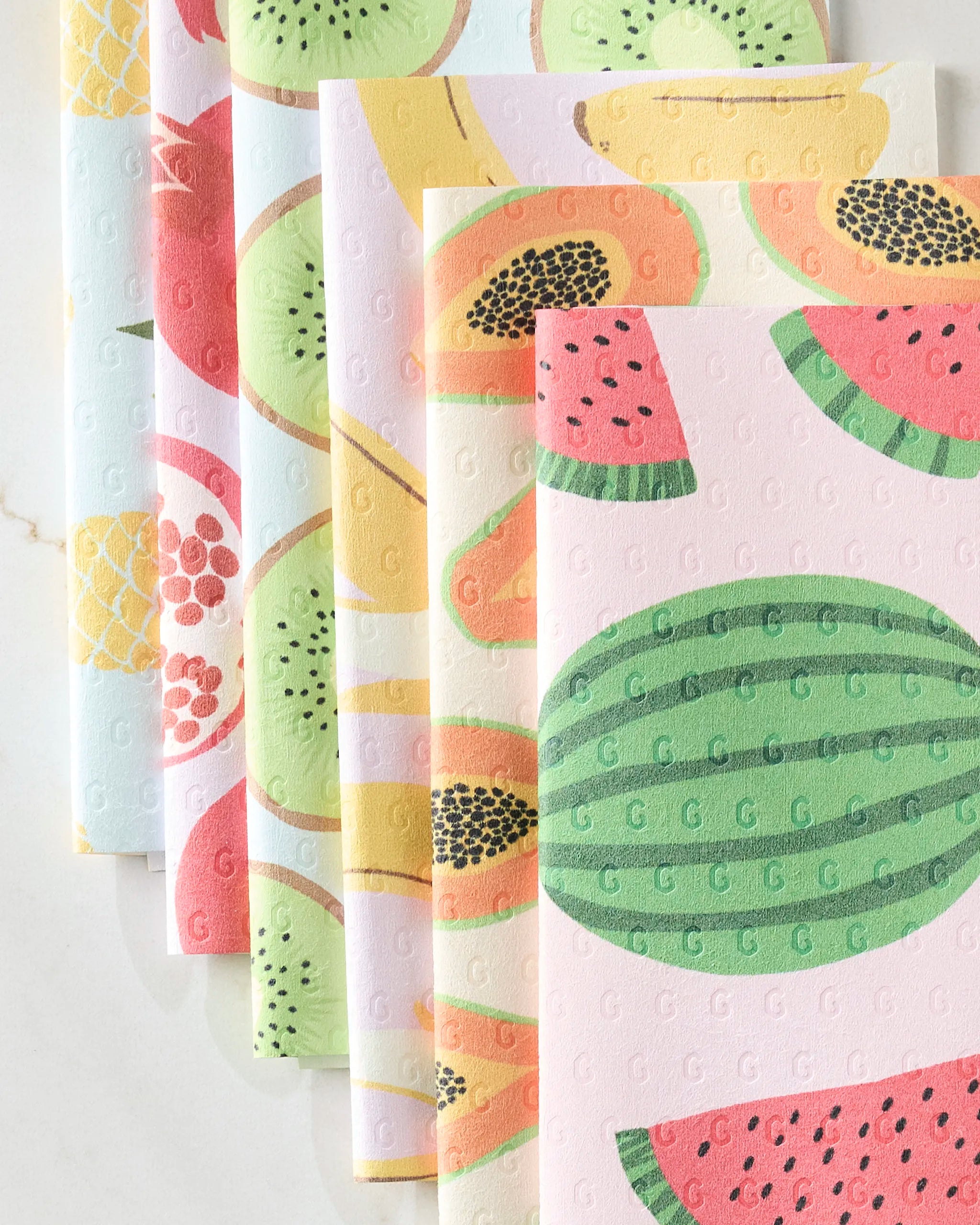 GEOMETRY's Sweet Summer Mix 2 showcases five reusable, eco-friendly paper towels with watermelon, papaya, kiwi, pomegranate, and pineapple patterns. Each towel features embossed G letters and is arranged in a fan shape on a white surface.