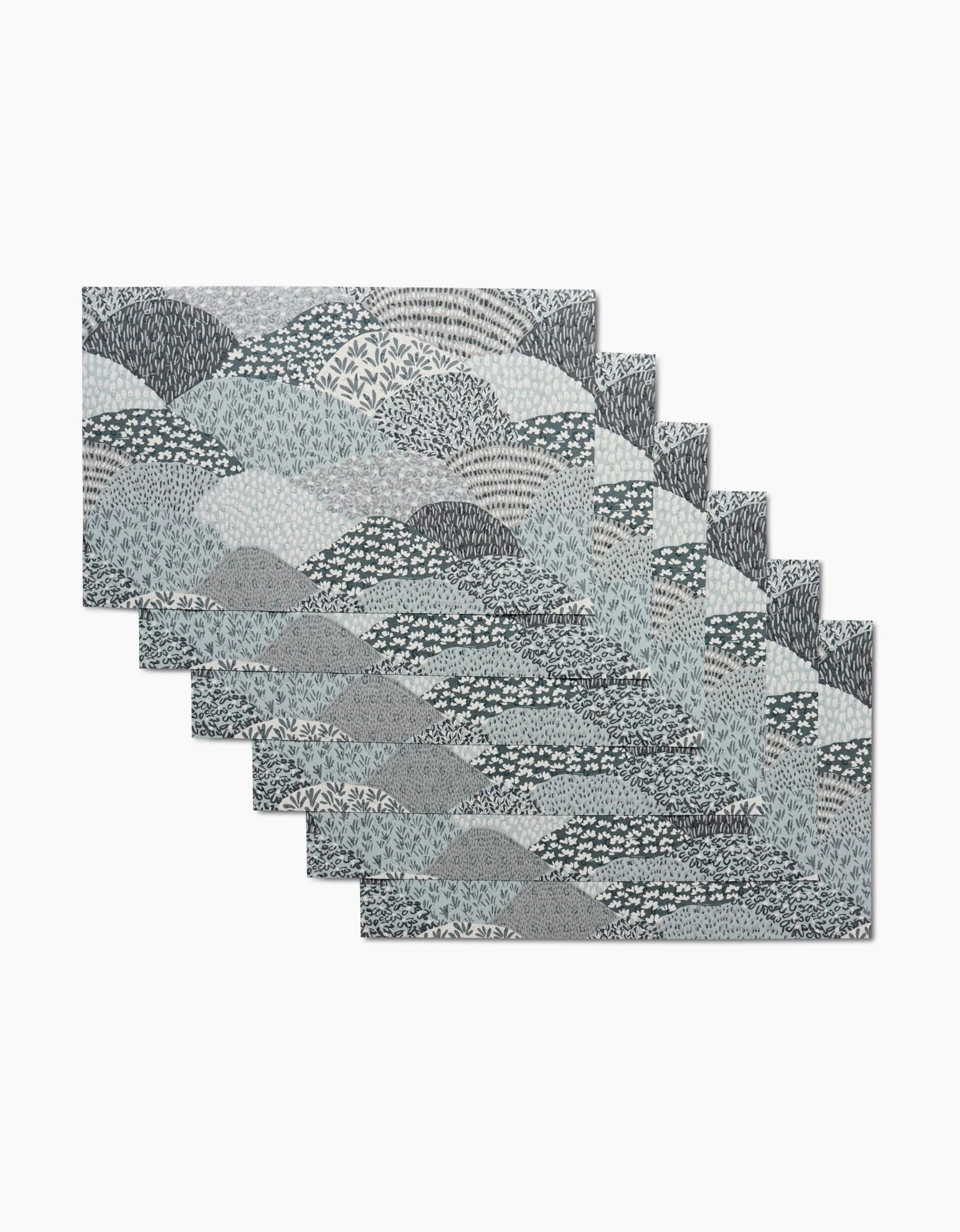 A set of six rectangular Sweet Valley Hills Green placemats by Hufton Studio, featuring a blue, gray, and white abstract wave and leaf pattern—an eco-friendly alternative to kitchen towels for stylish dining.