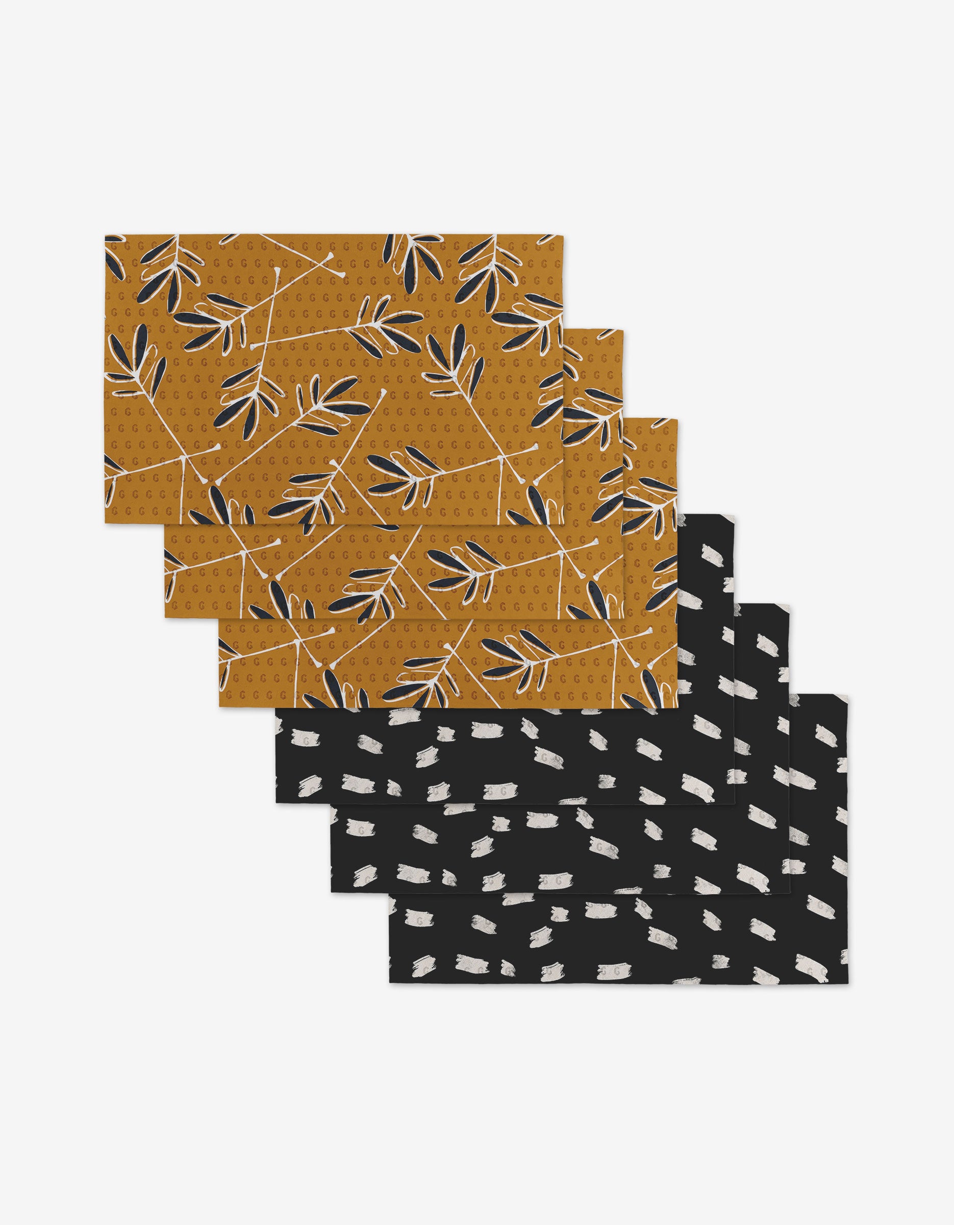 The GEOMETRY Tess And Dark set includes two styles of rectangular placemats—four with a mustard yellow leaf pattern and four with a black brushstroke design—that provide an eco-friendly alternative to disposable tableware.