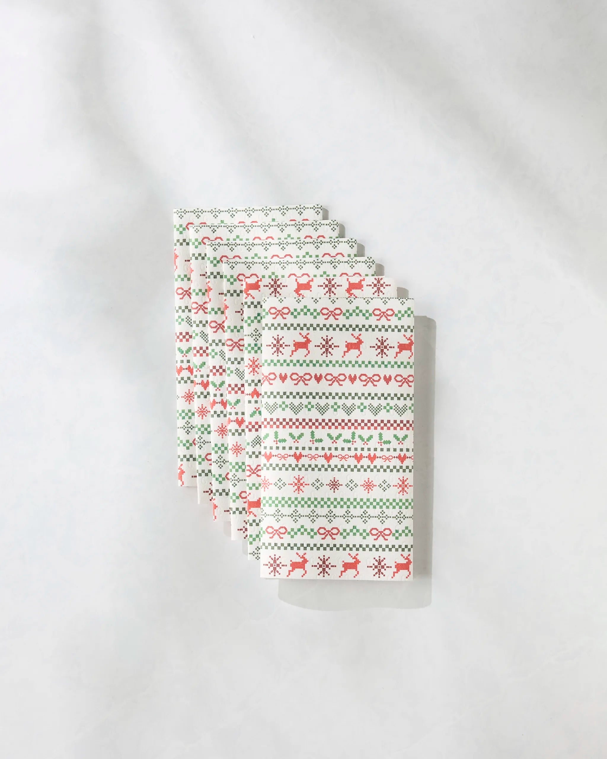 Five rectangular, reusable Geometry "Ugly Sweater Day" paper towels featuring festive patterns are fanned out on a light surface.