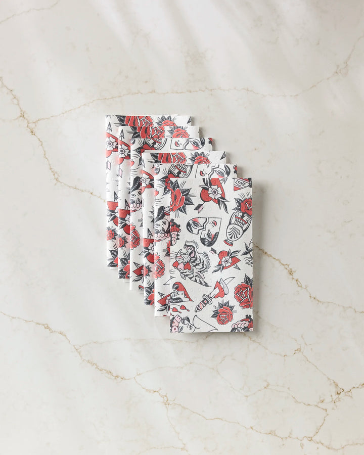 Six folded reusable "Valentine's Flash" paper towels by Cole Strem, featuring black and red roses, hearts, and vintage motifs, are neatly arranged on a light marble surface.