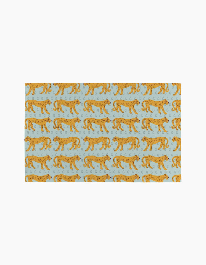The Walking Cheetah rug by Jasmine Blooms Designs is a light blue rectangular rug with orange cheetahs walking left and decorative swirls—an ideal eco-friendly accent for homes that use reusable paper towels.