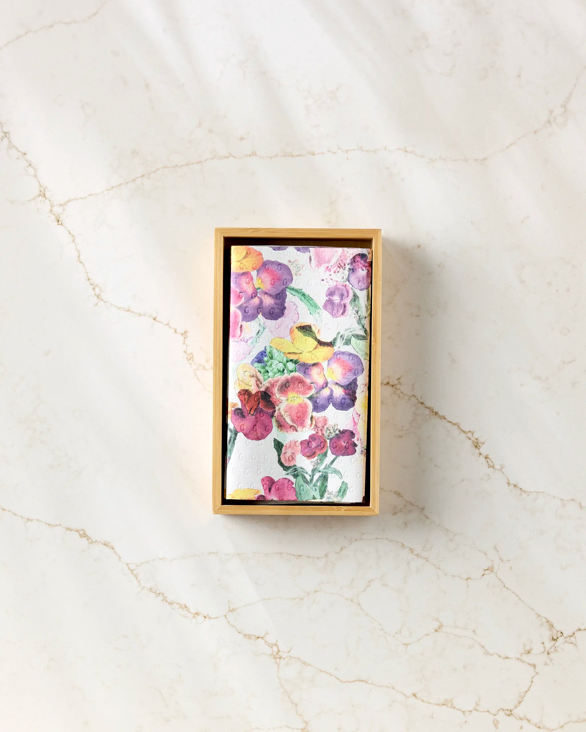 The Wallflower by Pascale Dilger is a rectangular box with a vibrant floral watercolor lid, set on light marble—ideal for storing reusable paper towels as an eco-friendly alternative to disposables.