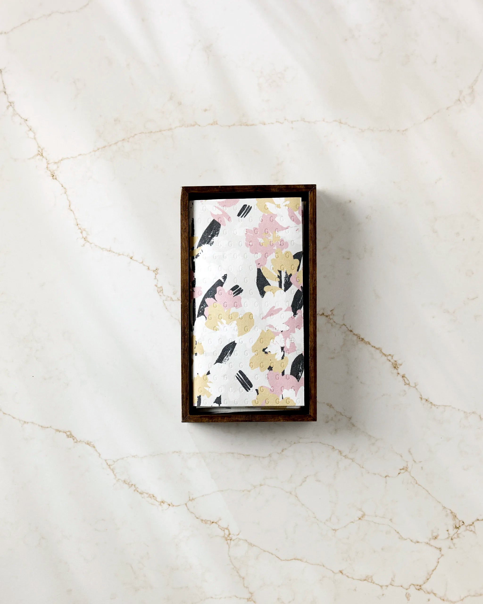 The Wilderness Floral rectangular wooden box by Toboggan Avenue features an abstract pink, yellow, white, and black lid—perfect for storing eco-friendly paper towels on your countertop.