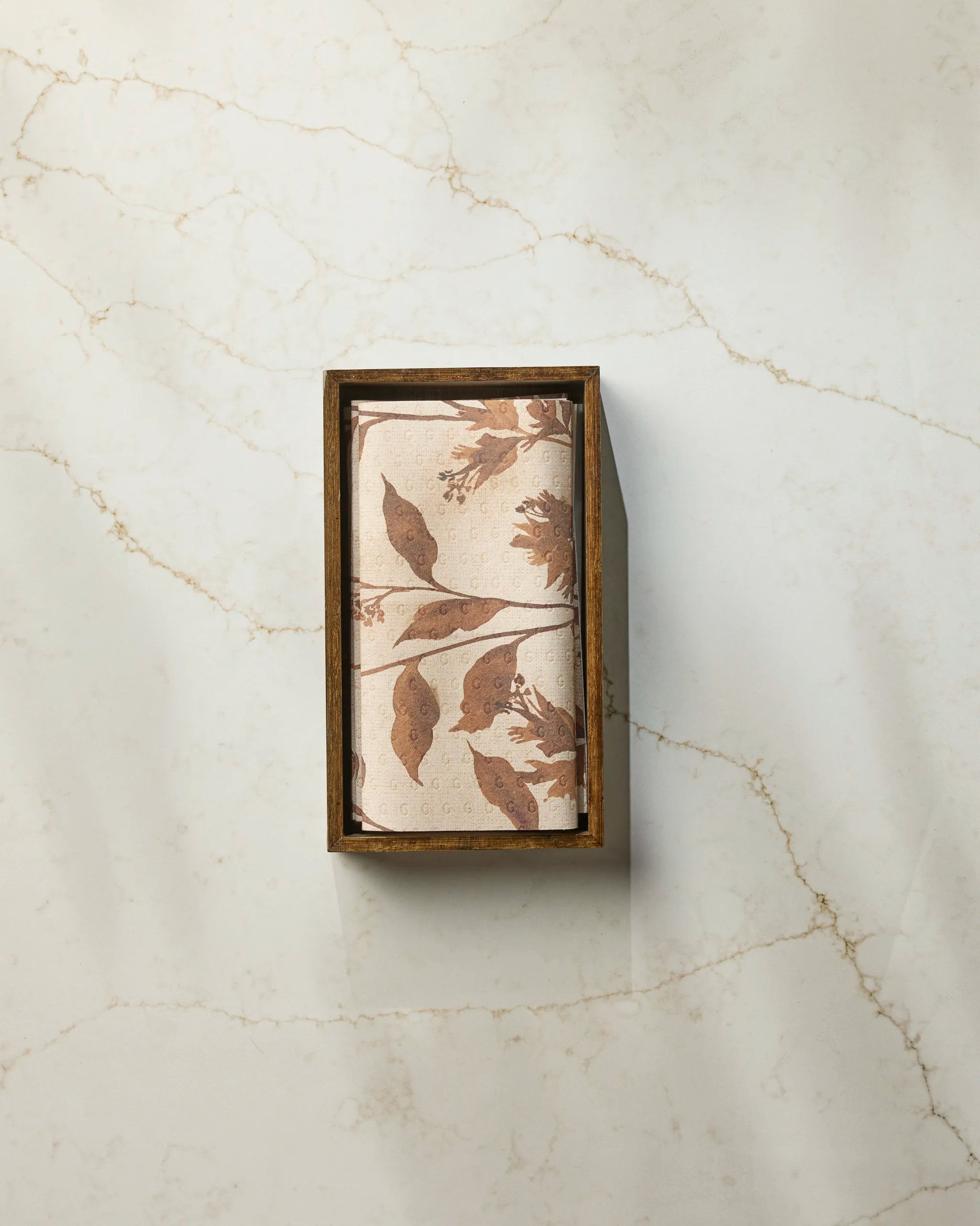 A rectangular box of Willowmere eco-friendly paper towels by Geometry, featuring brown leaf and bird designs, is placed on a light marbled surface.