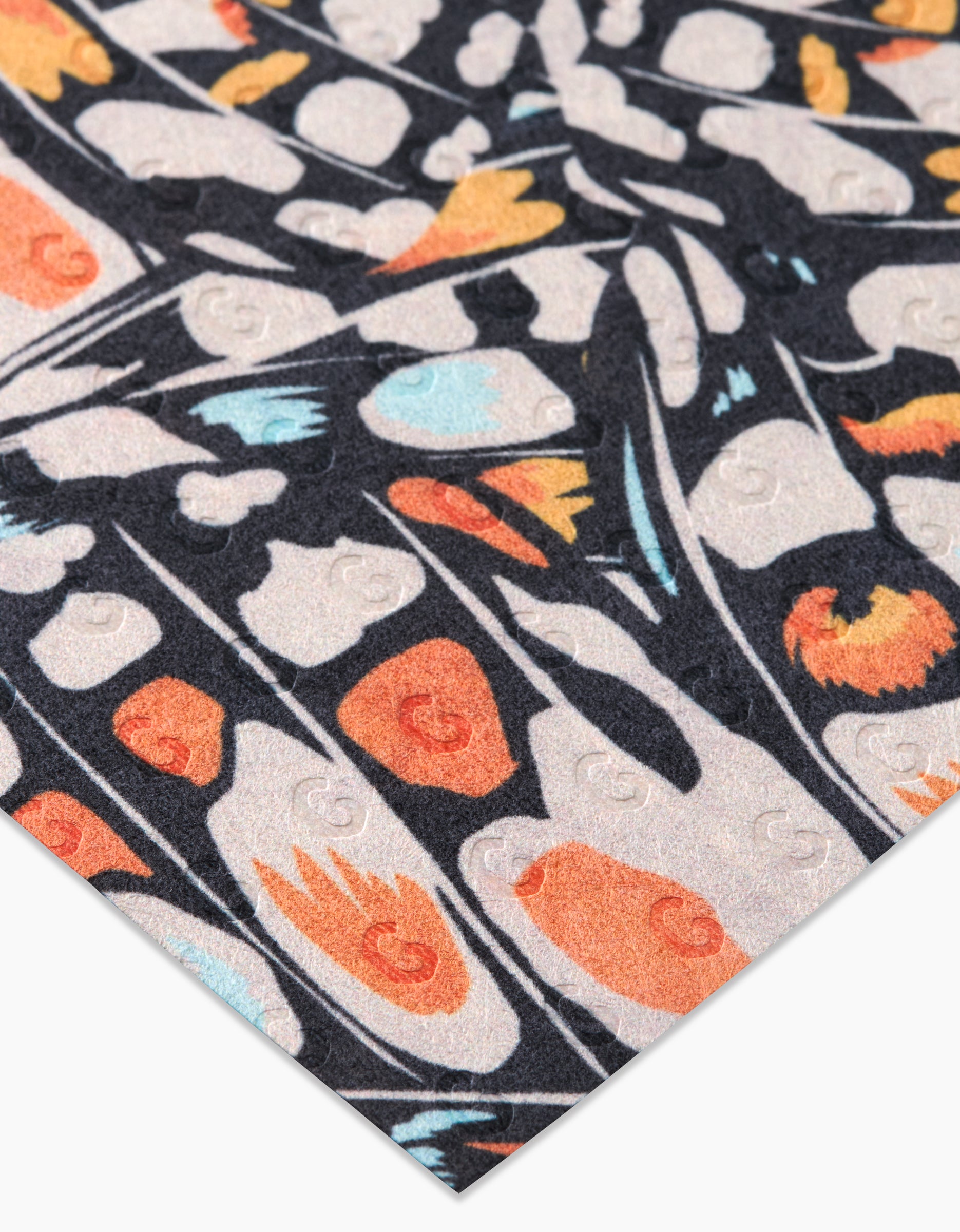 A close-up of GEOMETRY’s Wings in the Wind paper, featuring abstract orange, black, white, and blue designs with subtle embossed circles. Made from post-consumer recycled materials in a repeating geometric pattern.