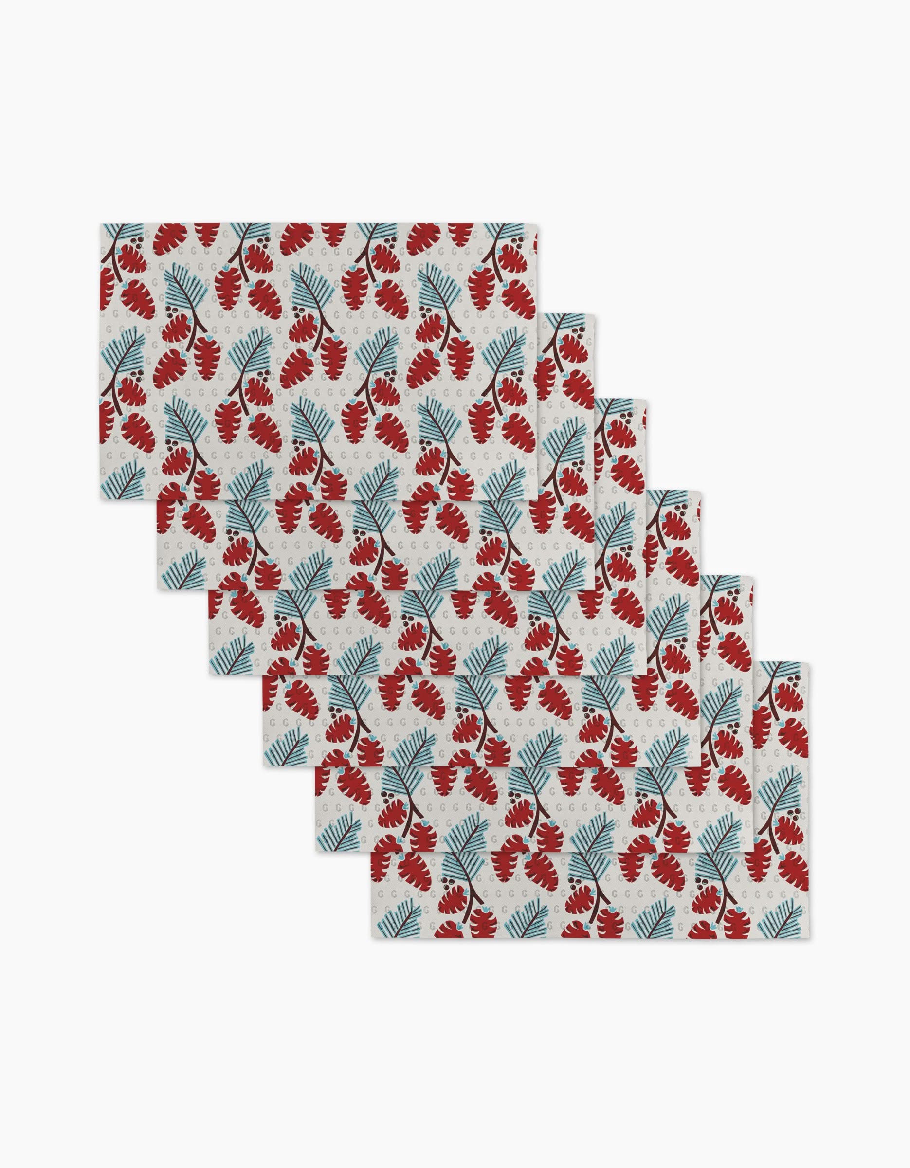 Six Winter Forage placemats from Geometry feature a red flower and blue leaf pattern on white. Use them as stylish placemats or reusable paper towels for an eco-friendly, versatile addition to your table setting.
